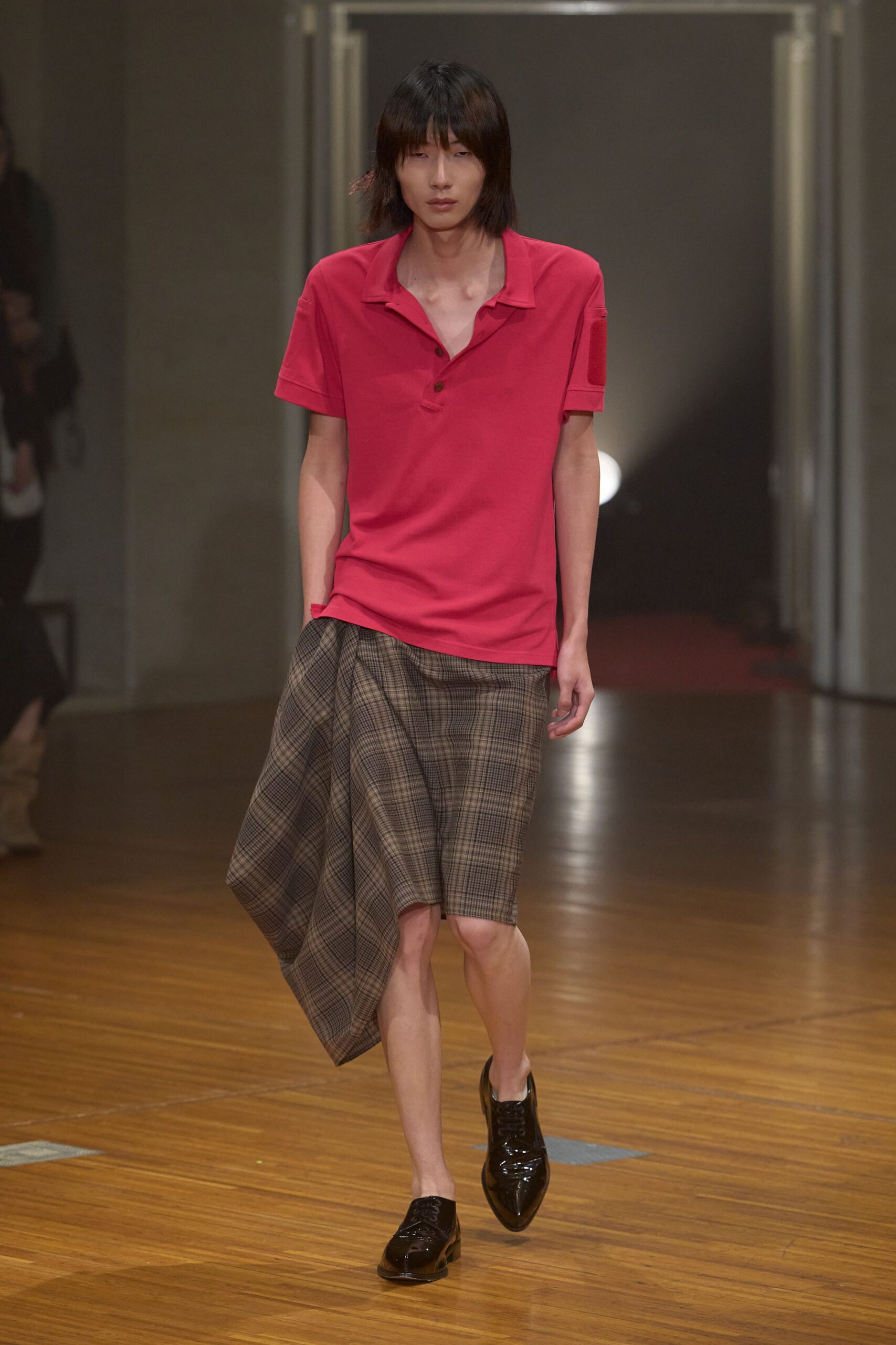 Raspberry knit polo with a loose open placket and dropped shoulders. Brown glen plaid skirt cut into a long lopsided drape. Black patent derbies with narrow laces and pointed toes. Walking across old auditorium floorboards after someone else's matinee.