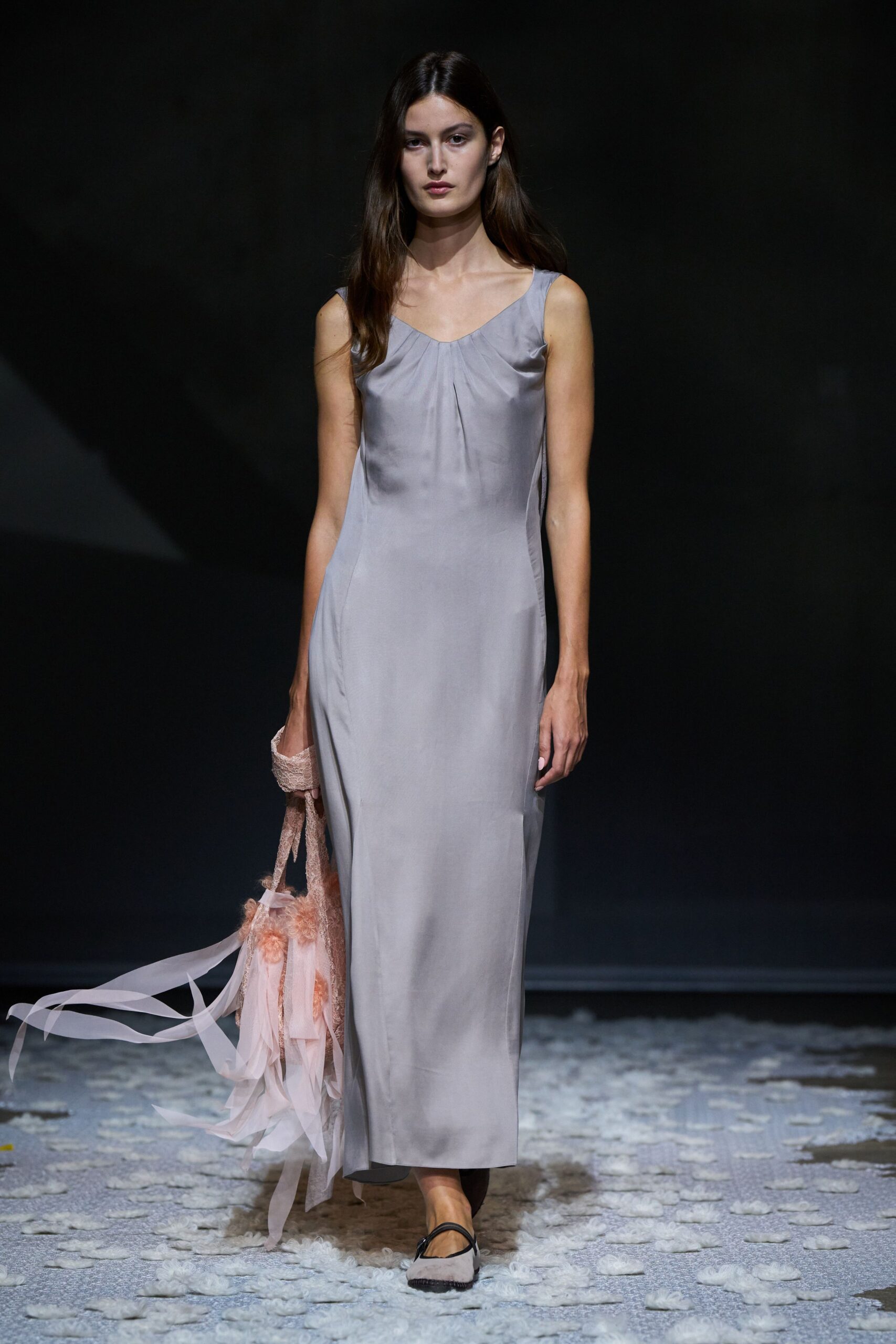 Pearl-grey satin slip dress, softly pinched into a shallow sweetheart neckline. Blush lace tote with rosette fluff and long chiffon streamers. Pale pink flats with a black Mary Jane strap. Crossing a hotel corridor barefoot in your head, bouquet ribbons snagging the carpet.