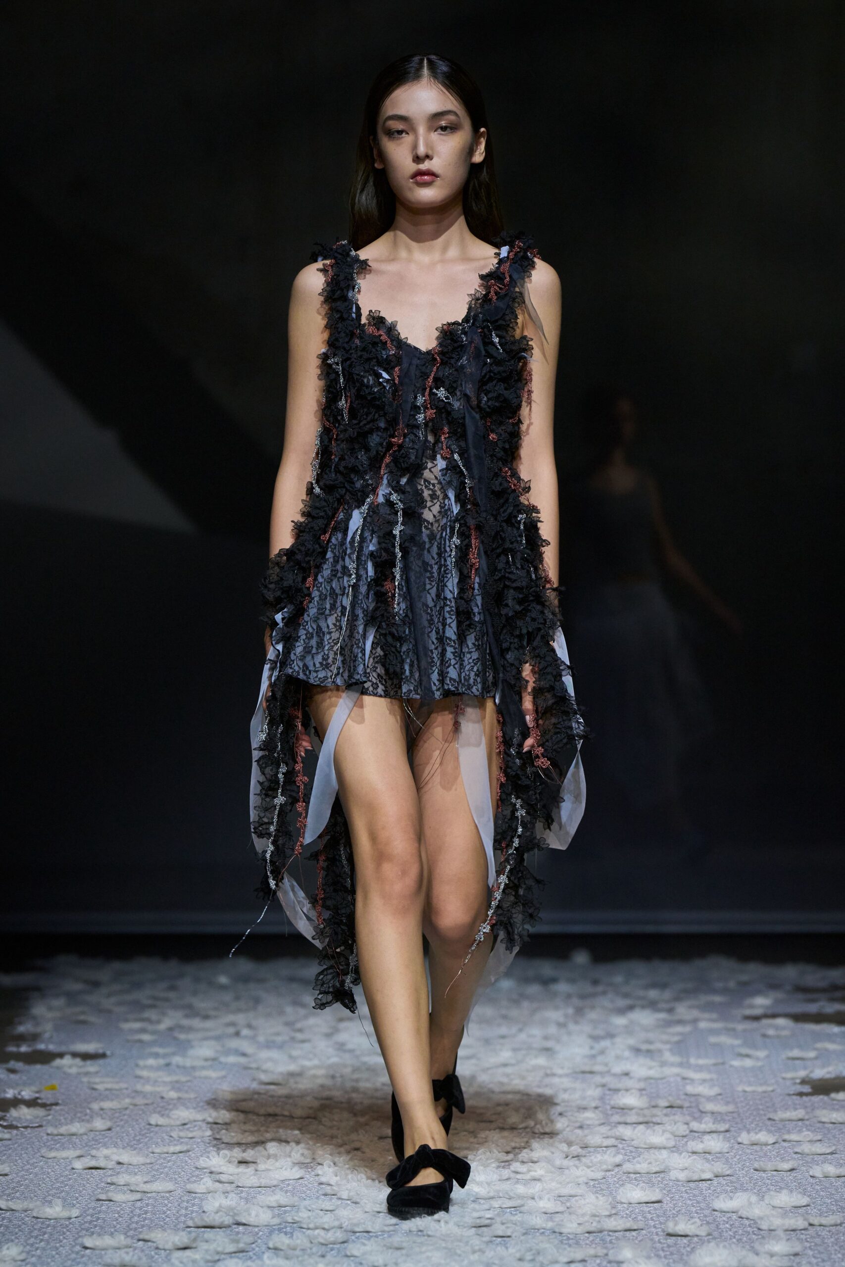 Black lace slip dress, crusted with shredded rosettes and trailing organza strips. Black velvet pumps with oversized bow fronts. Walking across a floor strewn with torn petals after the vows.