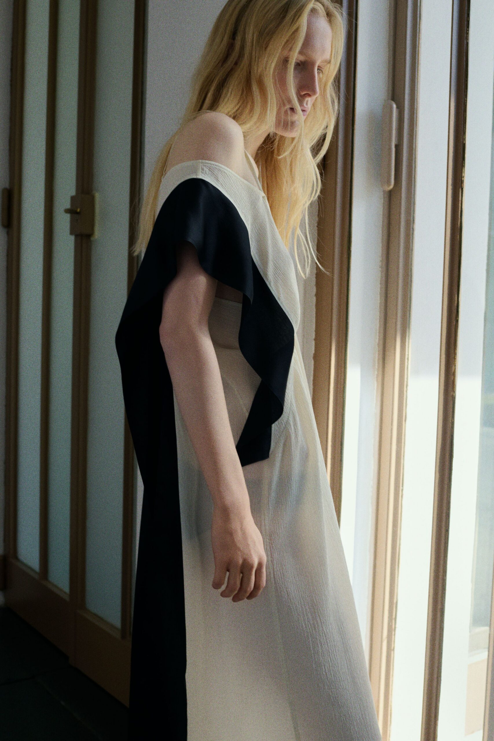 Ivory crinkled dress with a black satin cascade falling off one shoulder. Sun on the stairwell wall, the apartment still quiet after everyone left.