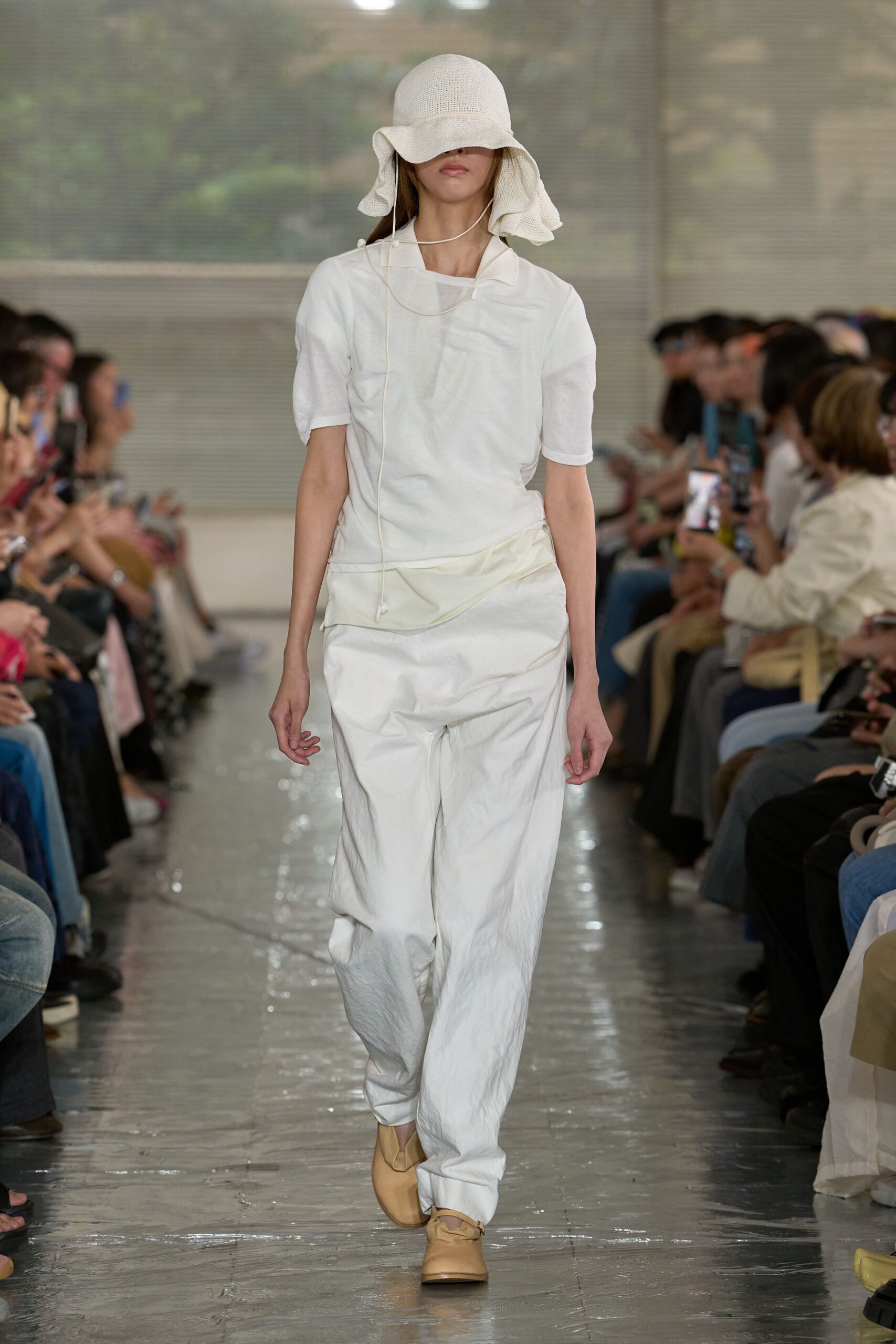 Ivory waffle-knit sun hat with a drooping brim, white short-sleeve top with a skewed collar, and chalk trousers in crinkled cotton slung low at the hip. Sand leather shoes. Like crossing a tiled courtyard just after the sprinklers stop.