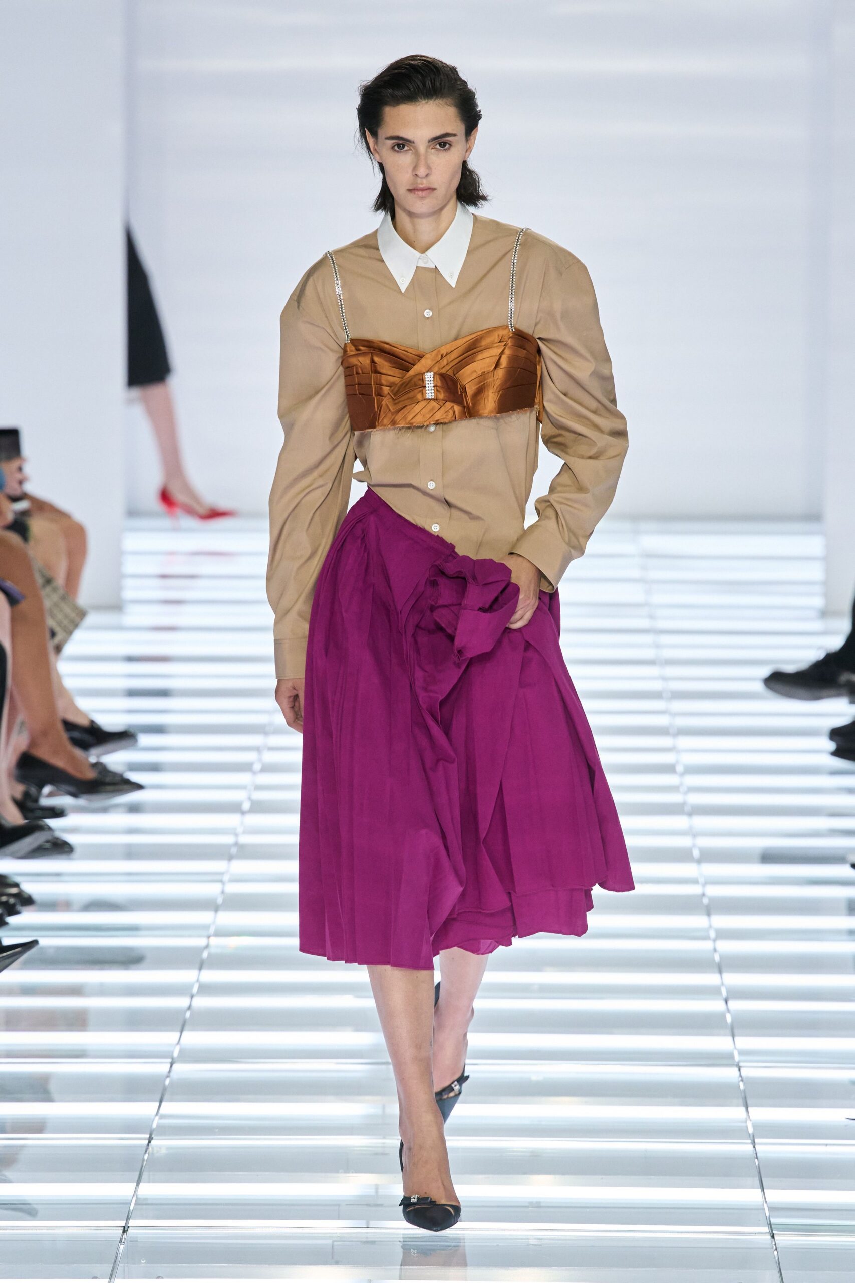 Sand cotton shirtdress with a stark white collar and off-center placket. Copper satin bustier, quilted in bands with diamanté shoulder straps. Magenta wrap skirt, knife-pleated and knotted into a bulky side ruffle. Black pointed flats with a tiny crystal buckle. Walking into a registry office with the bouquet left in the car.