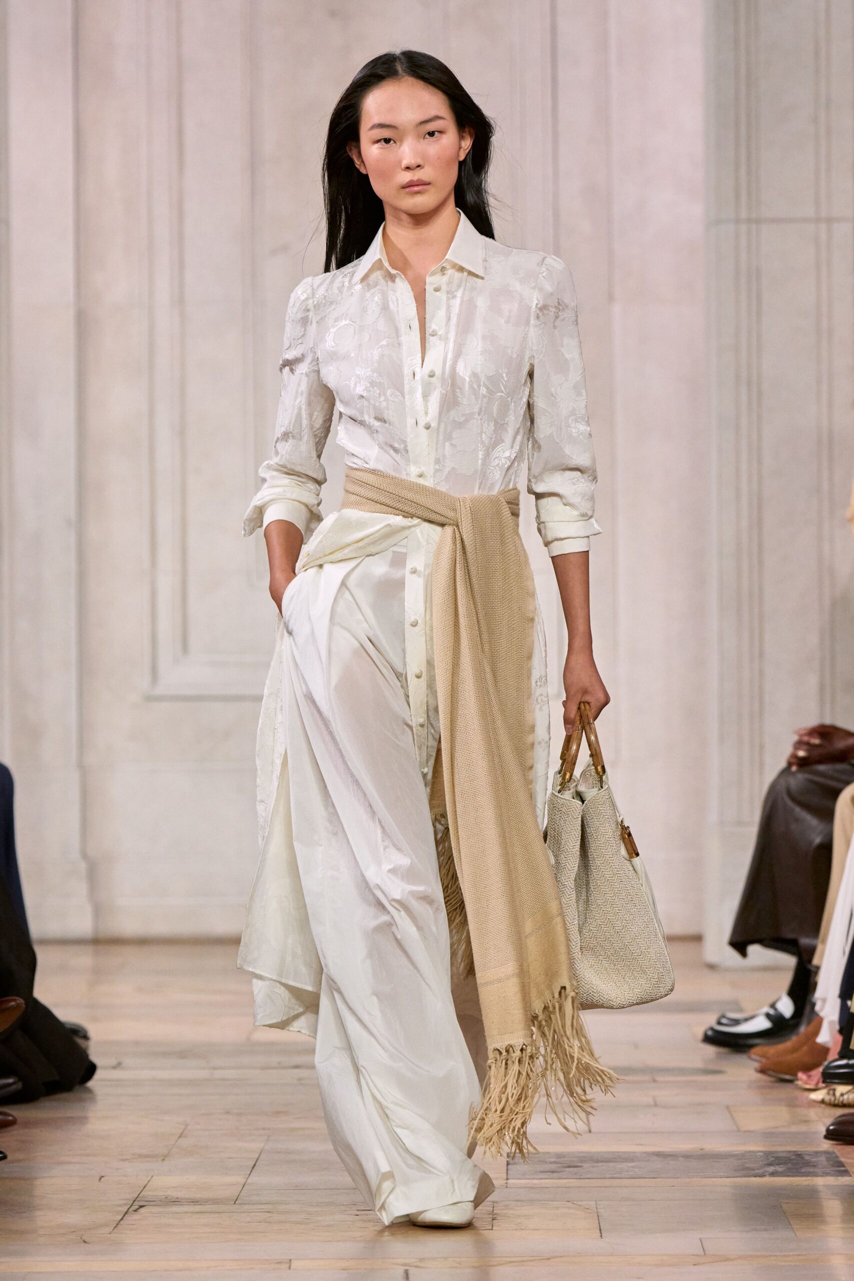 Ivory floral jacquard shirt dress, cuffs pushed up and buttons left open. Sand waffle-knit scarf knotted low, long fringe brushing the skirt slit. White satin trousers pooling softly over the shoes. Cream herringbone tote with bamboo handles. For checking into a hill hotel before the others wake.