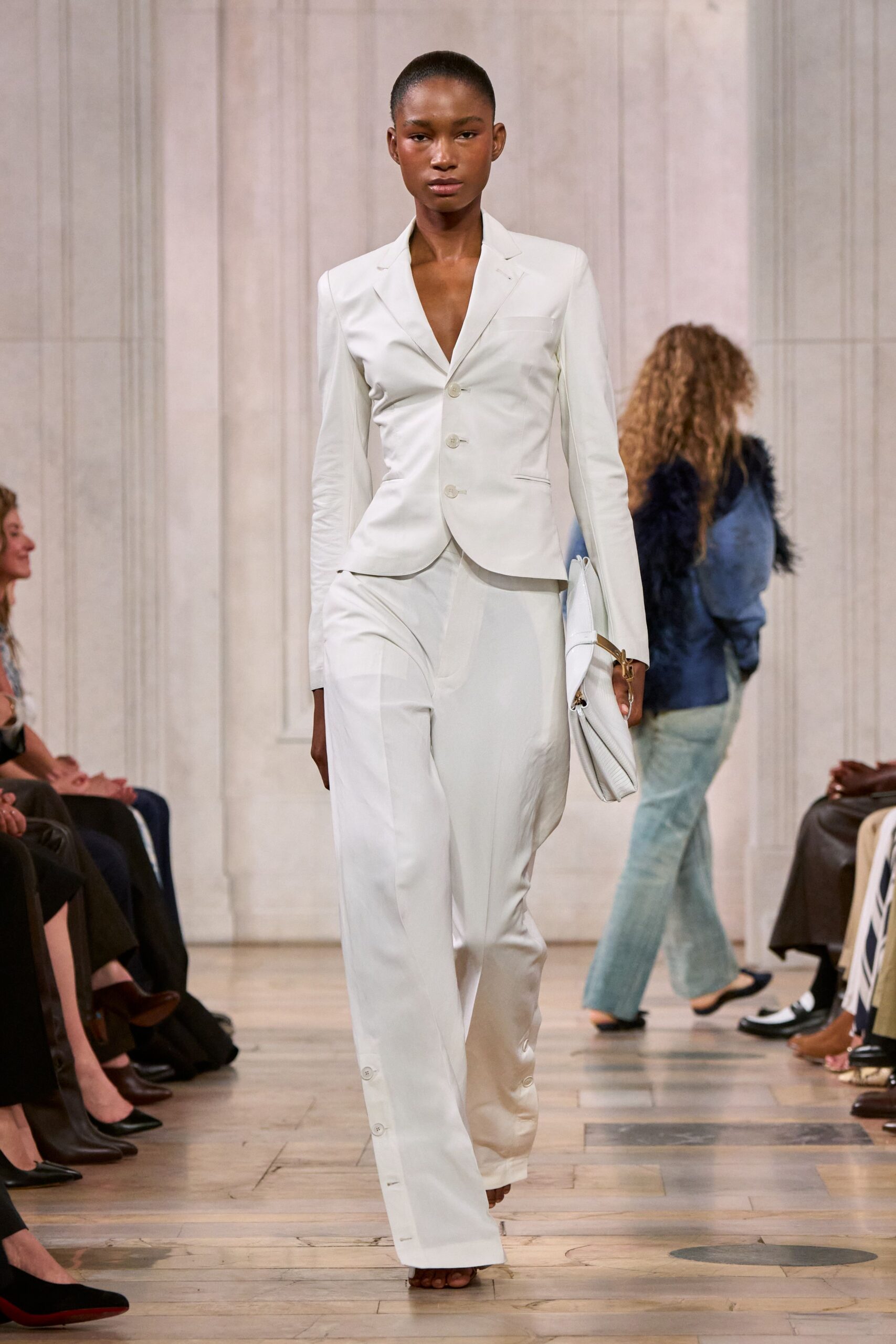 Ivory single-breasted blazer, cut close with a deep bare V. Fluid ivory wide-leg trousers, side vents fastened with tiny hem buttons. Soft white foldover clutch with a gold ring strap. For the courthouse steps after a wedding nobody planned months ahead.