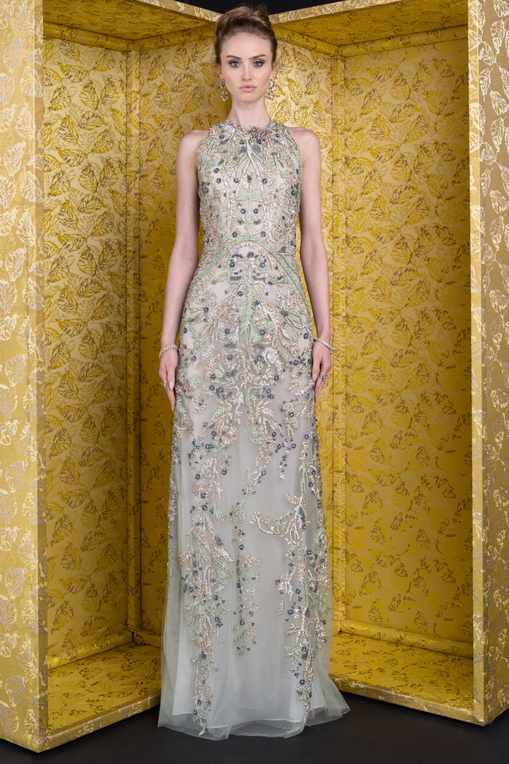 Ice-blue tulle column gown, densely beaded with silver vinework and blue florets. Dangling crystal hoops. Matching pavé bracelets at both wrists. At the museum benefit, standing under the last room's yellow silk walls.