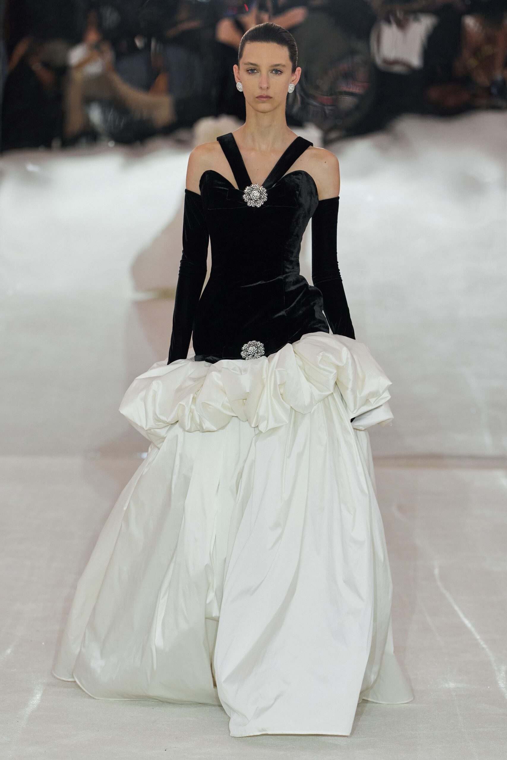 Round crystal cluster earrings. Black velvet bodice with off-shoulder sleeves and a rhinestone bow clasp. Ivory taffeta ball skirt, ruched into a swollen peplum at the hips. Descending a hotel staircase after midnight, still carrying the wedding cake in your hem.