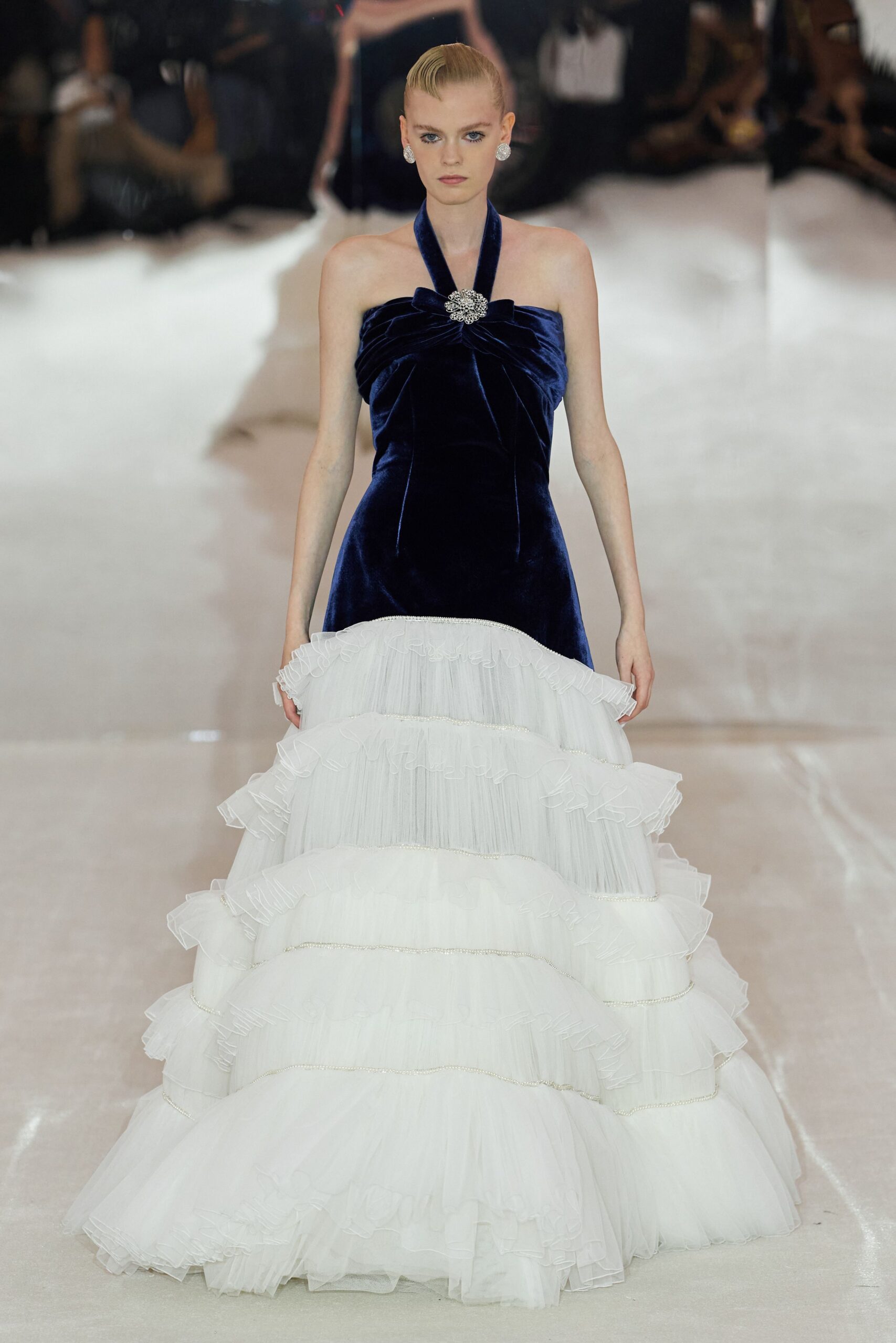 Midnight velvet halter gown, ruched bodice pinned with a crystal brooch. Ivory tulle ball skirt built in tiered ruffles with glittering bands. Round pavé clip earrings. For the staircase descent after everyone has been seated.