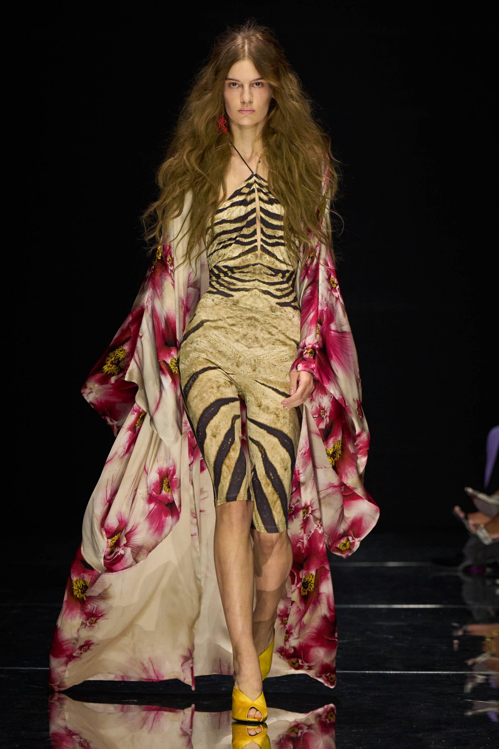 Floor-length ivory silk kimono coat scattered with oversized magenta hibiscus. Sand stretch catsuit printed in zebra stripes, ruched to a central front seam. Canary peep-toe pumps with a folded vamp. Single red tassel earring. Walking back from a beach wedding after kicking off the guest-list plan.