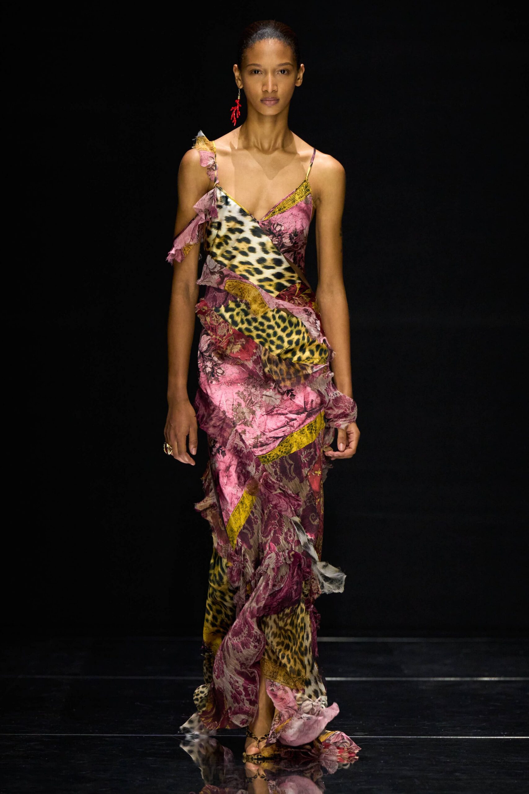 Bias-cut patchwork slip dress in pink brocade and leopard satin, raw ruffles spiraling off one strap. Leopard sandals with thin straps. Single red coral-branch drop. Walking back from a seafront wedding after the band has packed up.