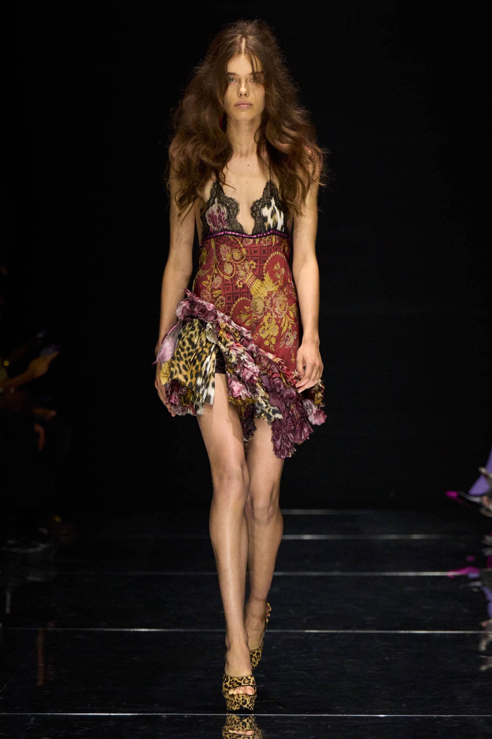 Burgundy brocade slip dress with black lace cups and a jagged ruffled hem of leopard and plum florals. Leopard peep-toe mules on a narrow platform. Walking into a casino lounge before noon, still wearing last night's lipstick.