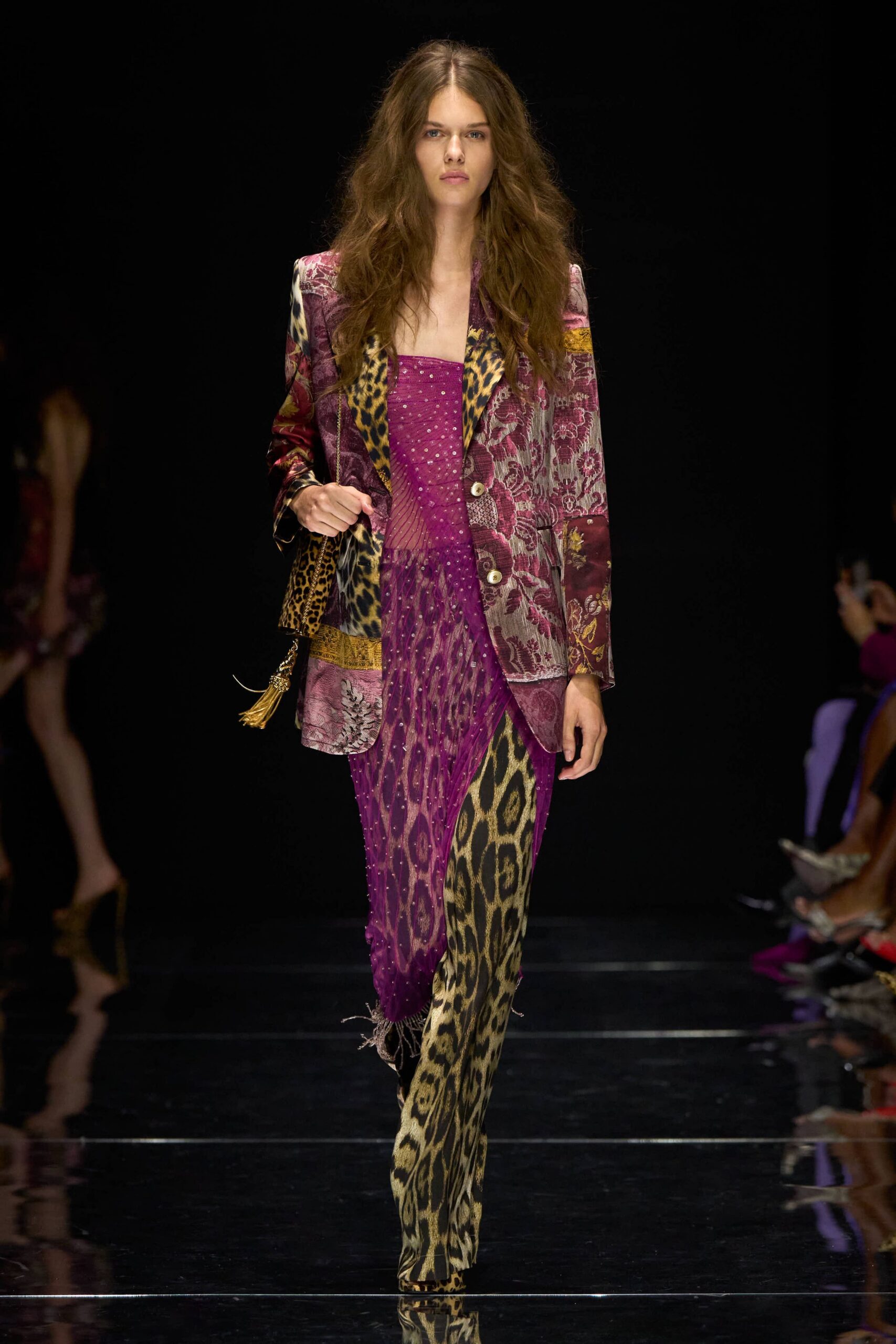 Patchwork blazer mixing plum brocade, leopard panels, and two pale horn buttons. Magenta beaded mesh dress, one side draped into a fringed scarf panel. Leopard trousers cut long and narrow under the sheer hem. Gold chain bag with a swinging tassel. Walking into a casino bar before midnight, already impossible to ignore.