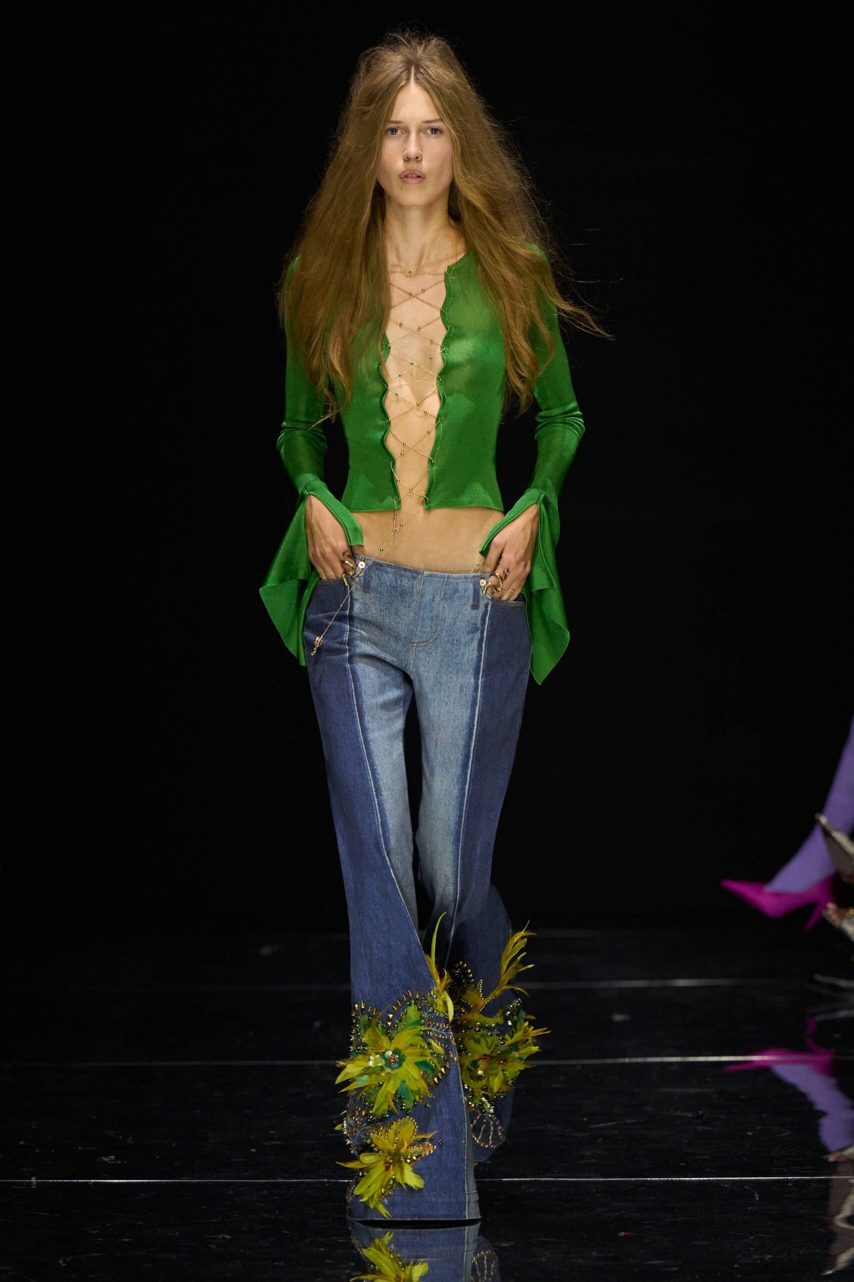 Sheer grass-green knit top, plunging front latticed with fine chains. Low-rise flared jeans, pieced in two blue washes with pressed seams. Denim boots overgrown with chartreuse feather flowers and beaded vines. Walking across a hotel lawn after midnight, shoes wet with sprinklers.