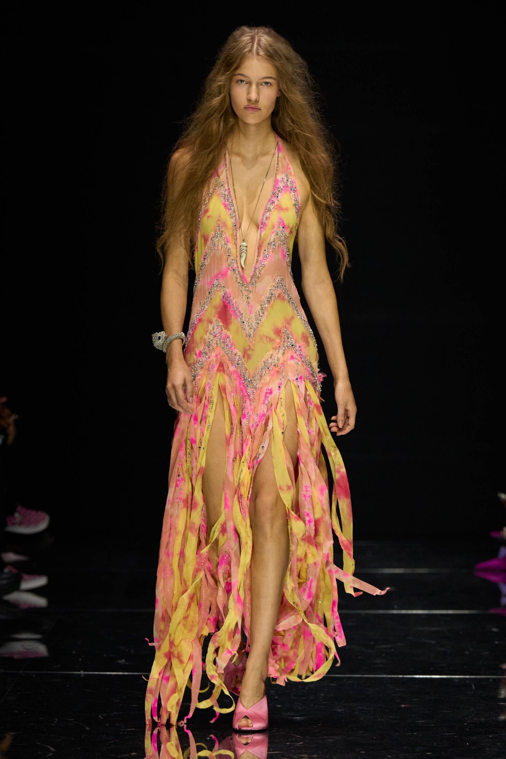 Plunging tie-dye slip dress, silver beaded chevrons and streaming shredded hem. Long cord necklace with a small tusk pendant at the sternum. Wide silver cuff, crusted with rhinestones. Pink peep-toe mules in smooth satin. Walking off the beach fair after dark, glitter still stuck to your collarbone.