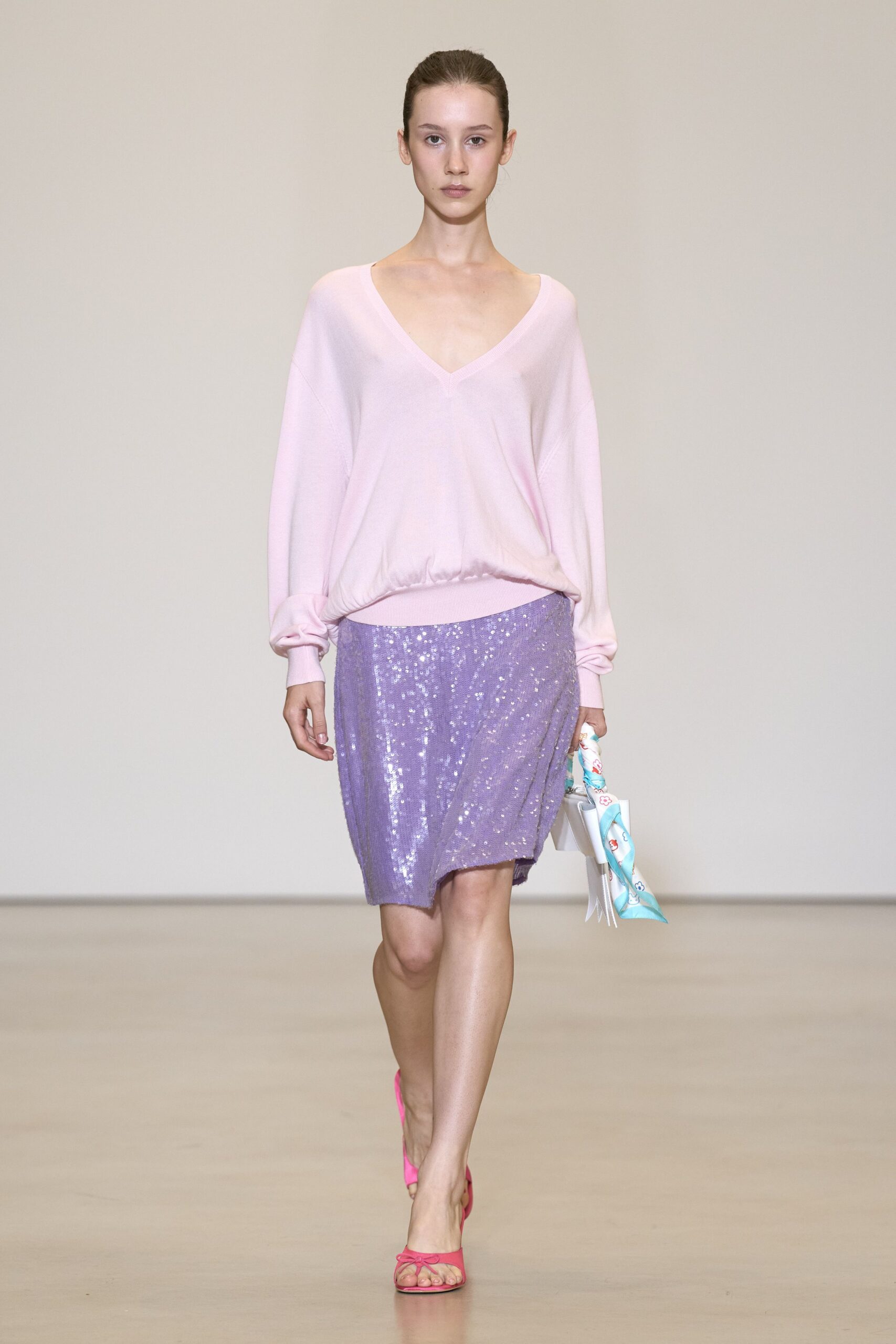 Blush fine-knit sweater cut with a deep V and bloused ribbed hem. Lilac sequined skirt draped askew, one side dipping lower at the thigh. White mini bag wrapped with a sky-blue printed scarf. Hot-pink thong sandals with a tiny bow at the toe. Hotel breakfast terrace, ordering fruit when last night's glitter is still clinging.