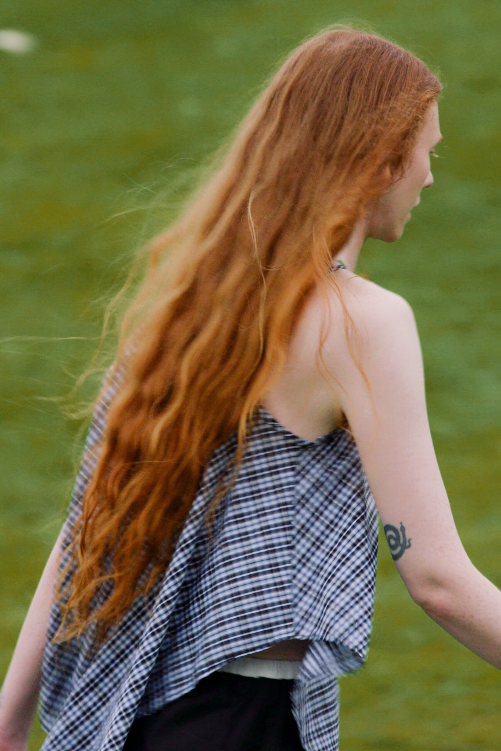 Black-and-white micro-gingham camisole, cut on the bias with a fluttering handkerchief hem. Black skirt with a pale waistband peeking cleanly above it. Crossing a wet field after the picnic blanket has already been folded.