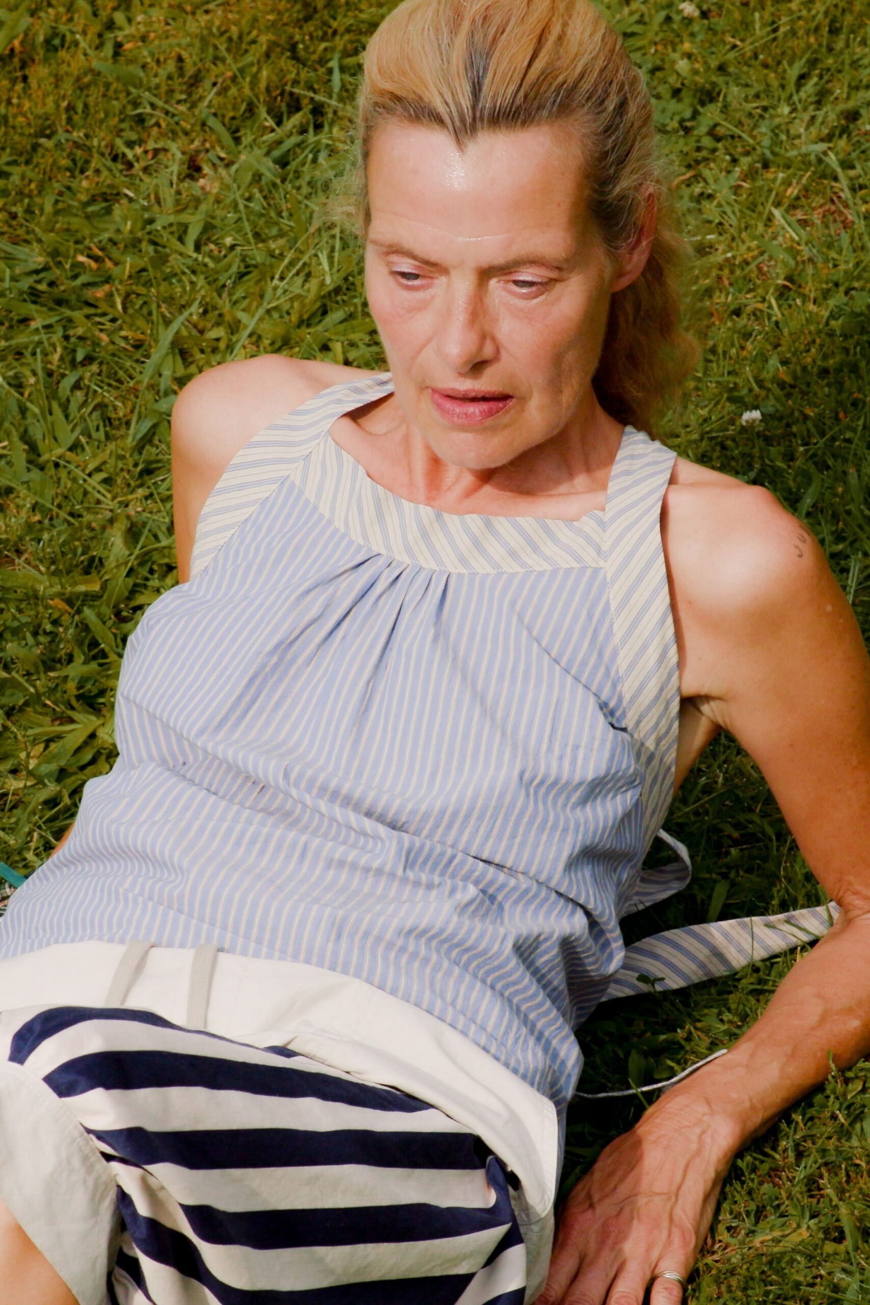 Pale blue pinstriped cotton top with a squared yoke and soft gathers. White skirt blocked with broad navy sailor stripes near the lap. Stretching out in grass after the ferry picnic has gone quiet.