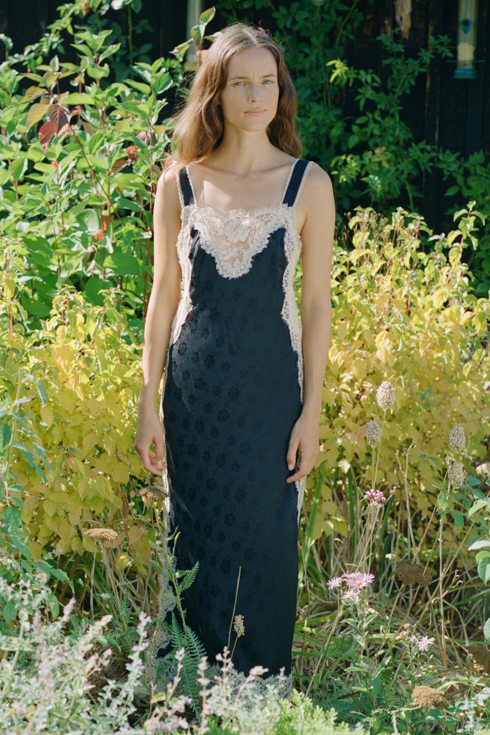 Ink satin slip dress with scalloped ivory lace inset and hem. Wide black shoulder straps, the lace edging slightly irregular at the side. Walking through the herb garden after lunch, bees still working the last flowers.
