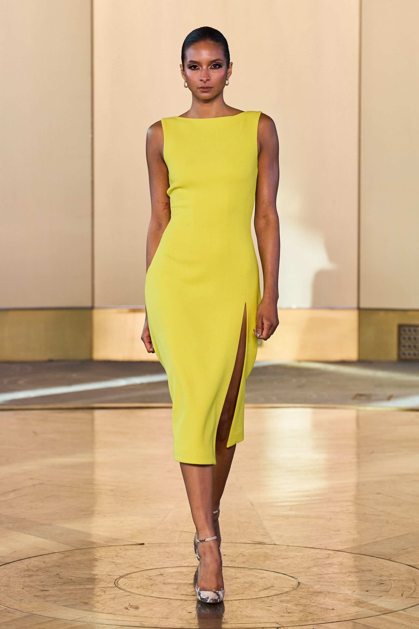 Acid-lime sheath dress, boat neckline and thigh slit cut clean at one side. Small silver hoops. Python pumps with glittered ankle straps. Walking into a hotel atrium just as the sun slides off the marble.
