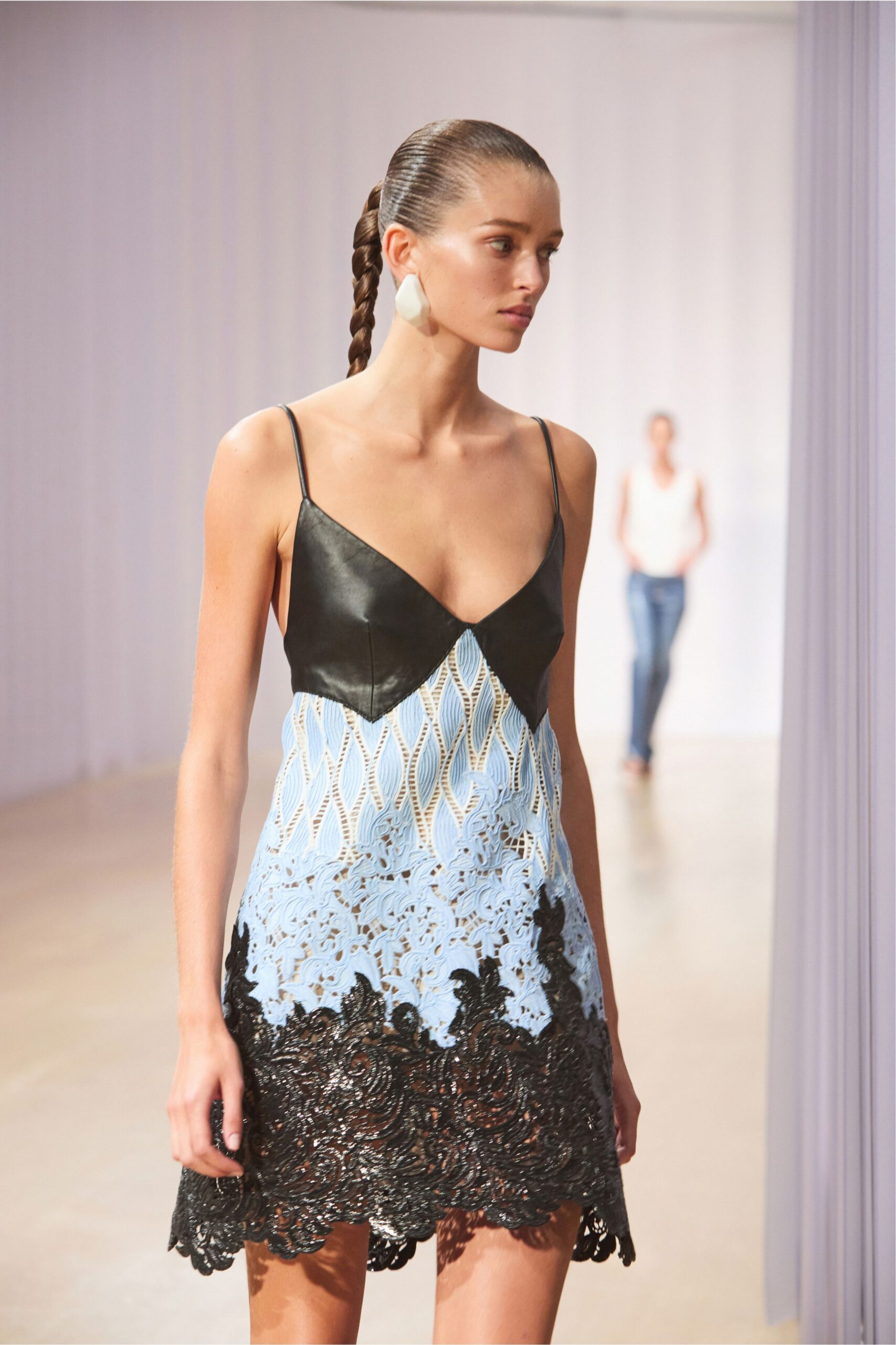Single milky resin drop, faceted like a smoothed stone. Black leather bra cups over sky-blue guipure, dissolving into black cord lace hem. Walking through a hotel atrium before anyone has claimed the loungers.