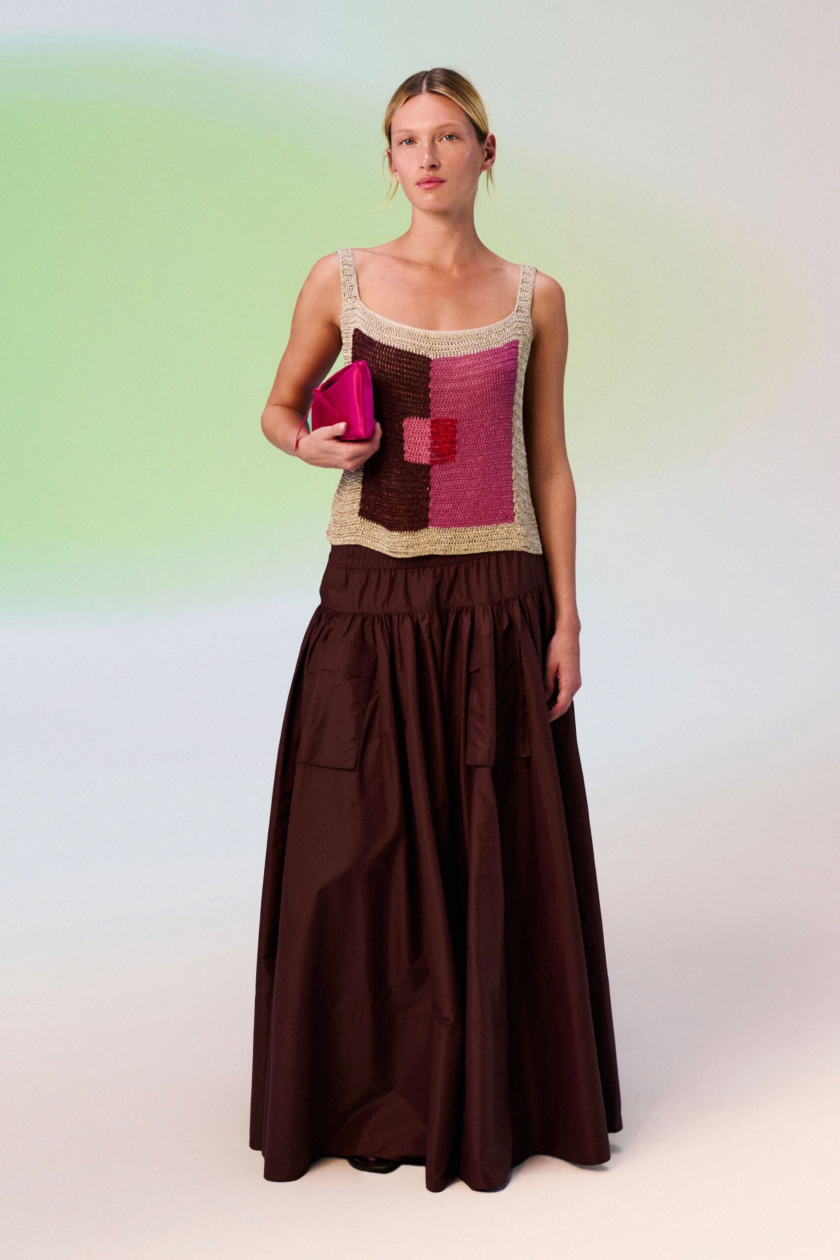 Hand-crocheted tank in oatmeal, chocolate and rose color blocks. Hot-pink satin clutch tucked flat under one arm. Dark brown poplin maxi, dropped waist gathered above patch pockets. Black peep-toe shoes barely visible under the hem. Walking into a hotel brunch with lipstick already on the coffee cup.
