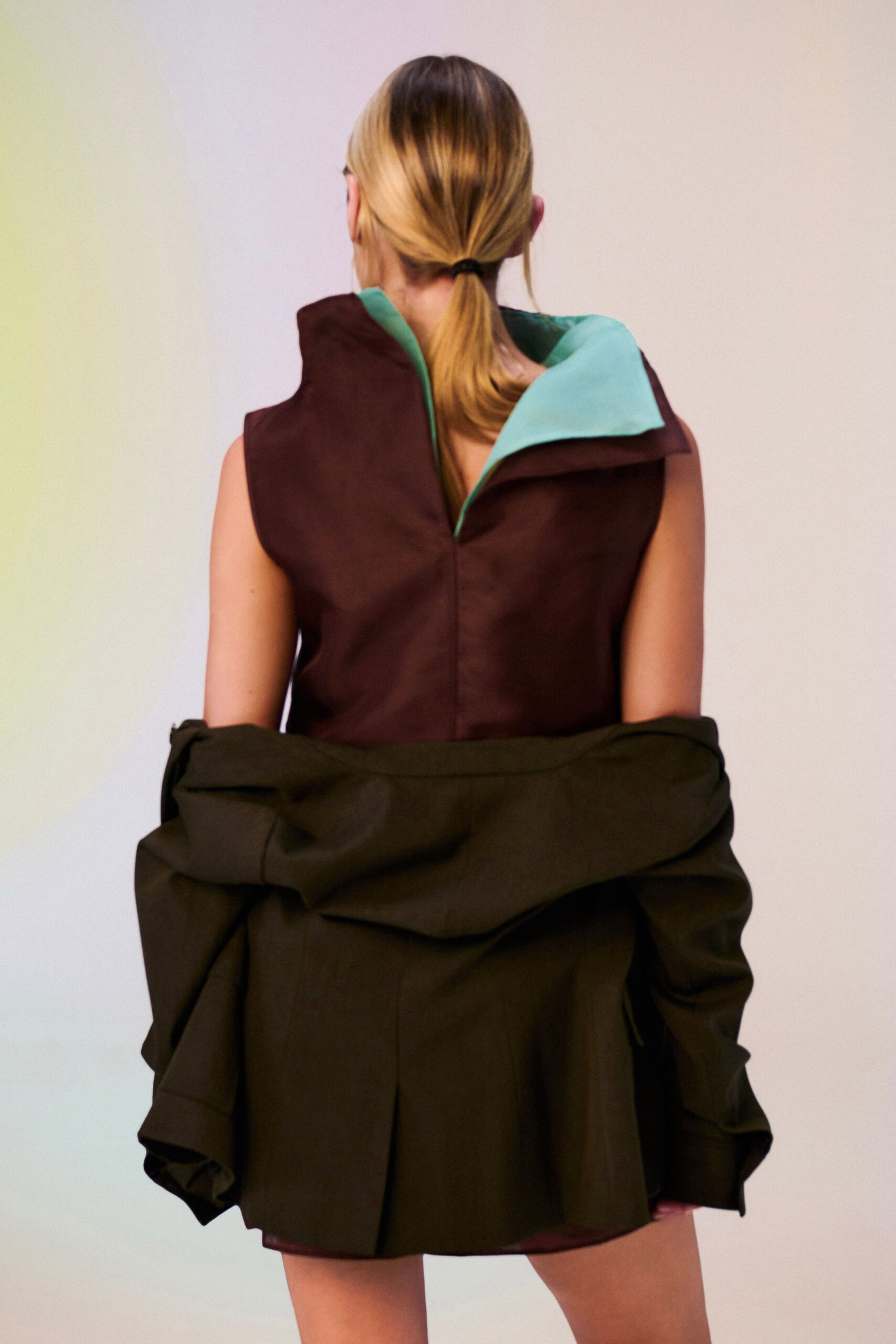 Aubergine sleeveless mini with a mint standing collar folding open at one point. Black tailored jacket shrugged to the elbows, hem jutting into a stiff peplum flare. Stepping out to the motel walkway after the pool has emptied.
