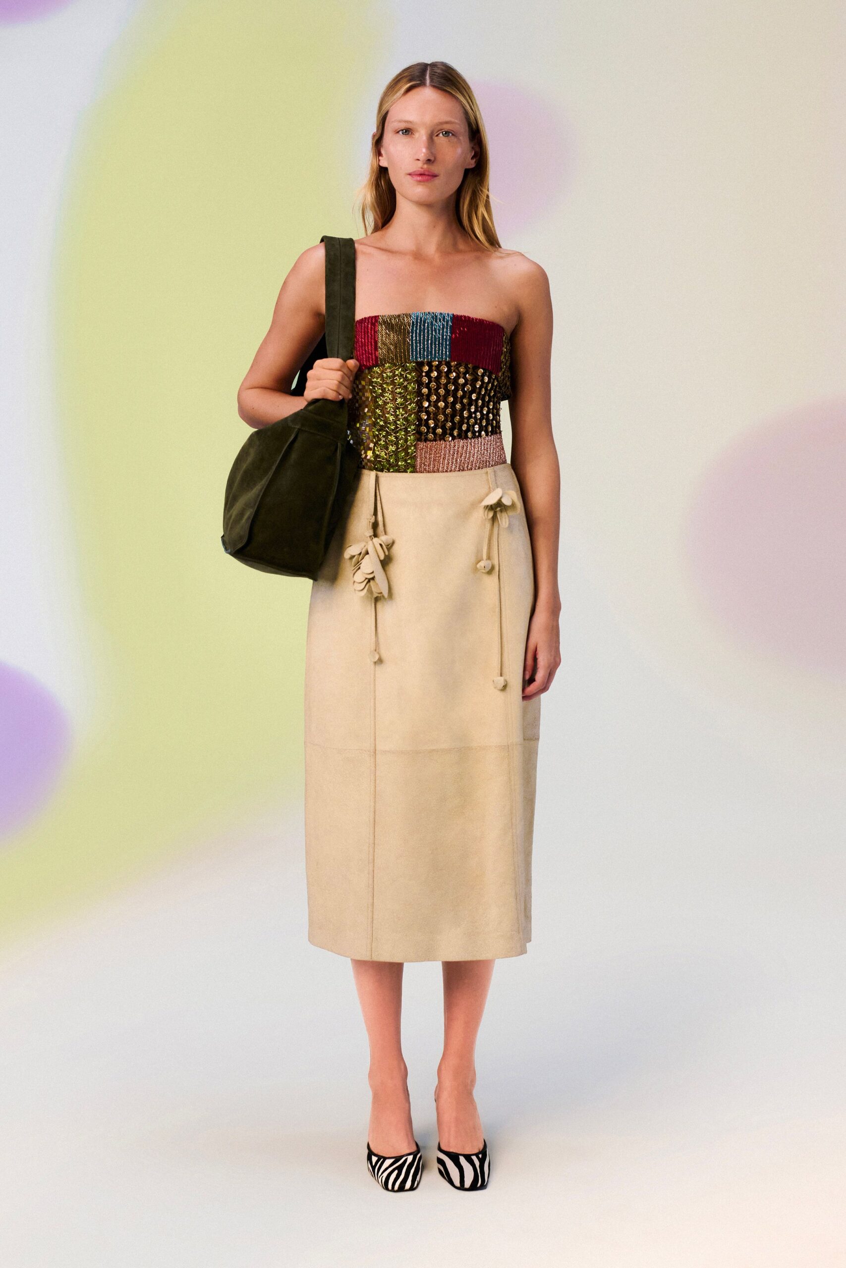 Slouchy moss suede shoulder bag with a broad flat strap. Patchwork bandeau in metallic woven blocks and bead-dotted panels. Butter suede wrap midi, tied with dangling petal-tipped cords. Zebra-print pumps with a squared toe. For drifting between gallery stalls at a hotel craft fair.