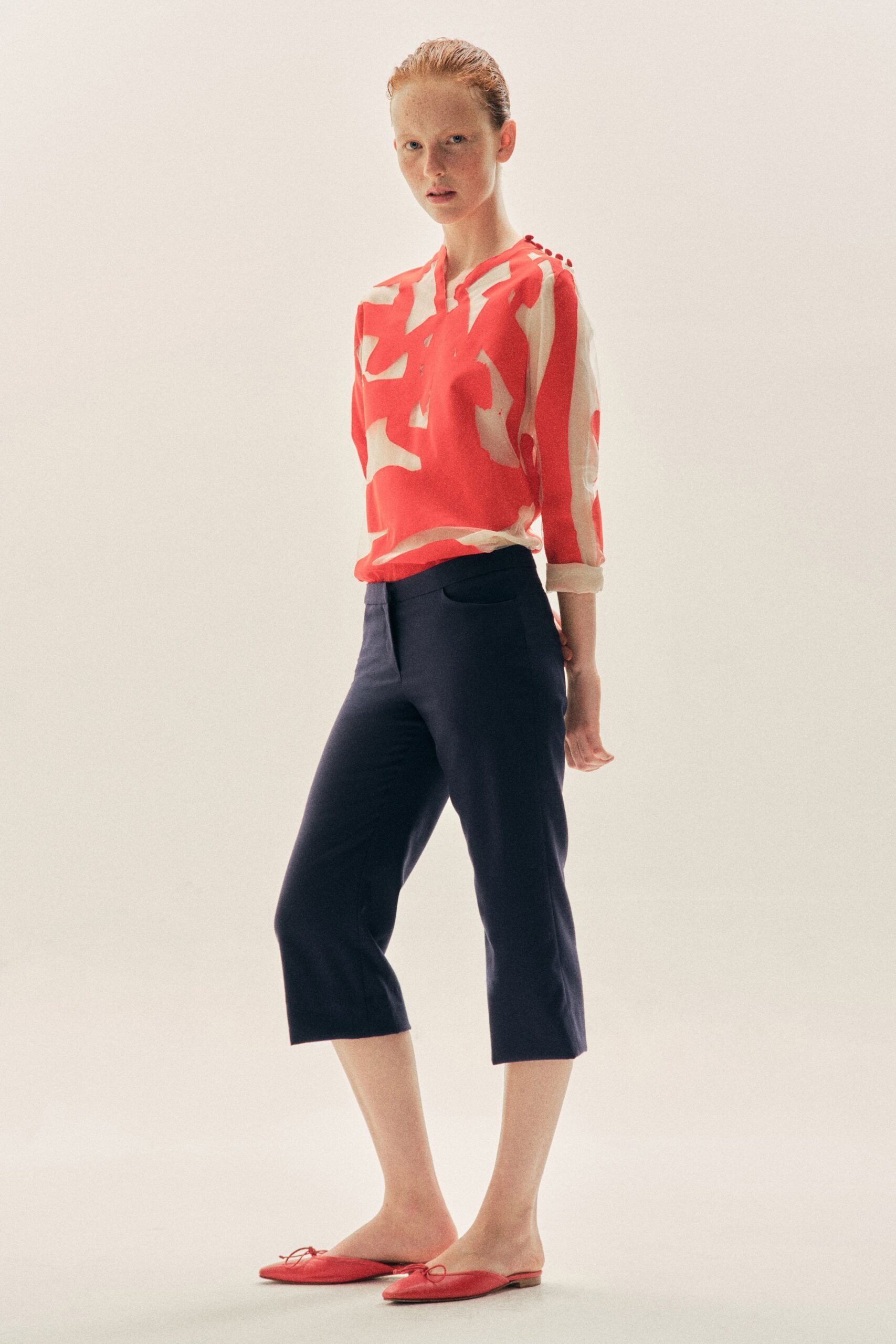 Coral and ivory printed blouse, rolled cuffs and tiny shoulder buttons. Ink cropped trousers with curved pocket openings and a flat front. Coral pointed mules tied with thin bow cords. For an afternoon ferry crossing with the wind coming sideways.