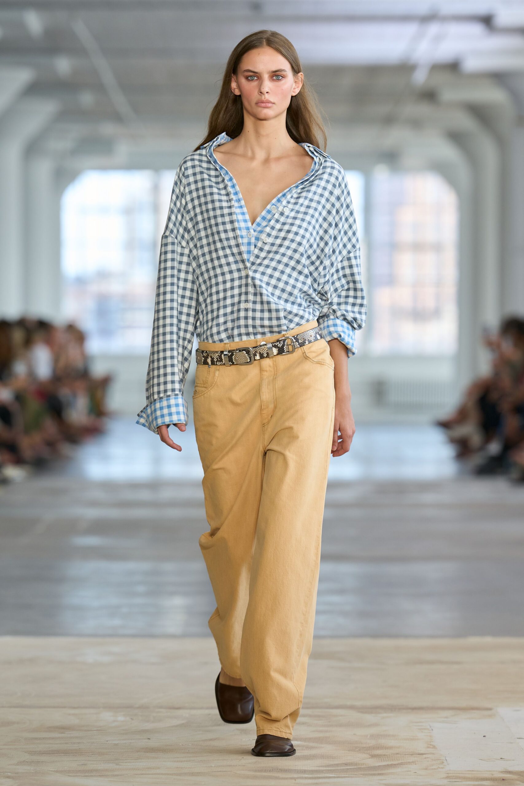 Blue gingham cotton shirt worn askew, one cuff turned back wide. Buttermilk twill trousers cut loose through the leg. Python belt with a double buckle sitting slightly off center. Dark brown square-toe flats. Sunday farm stand, peaches bruising in the paper bag.