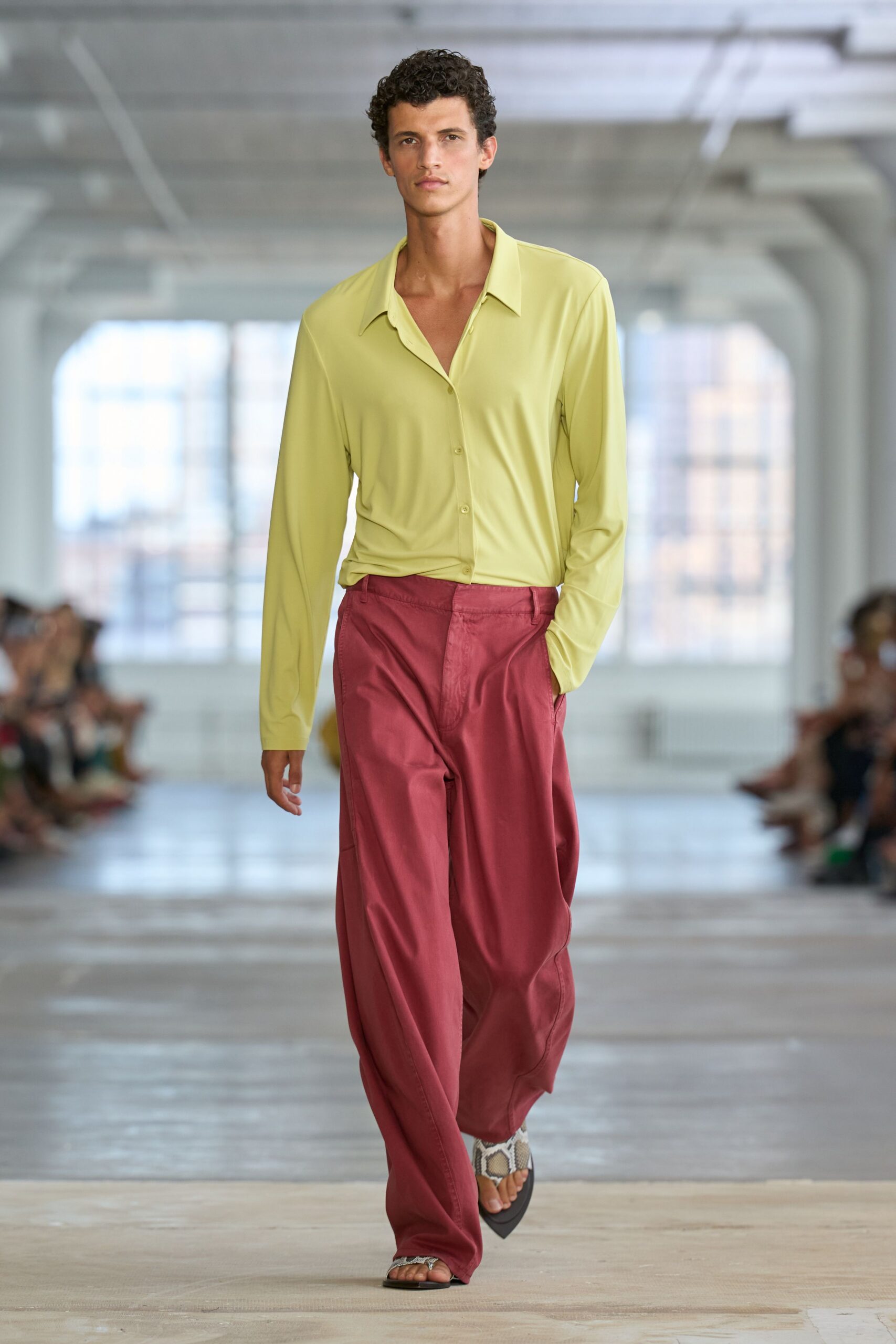 Lime stretch shirt with a liquid drape and long pointed collar. Rose satin wide-legs, pressed flat at the fly then pooling. Python-strap thong sandals on black pointed soles. Walking into a beachfront hotel lobby before the air-conditioning fully hits.