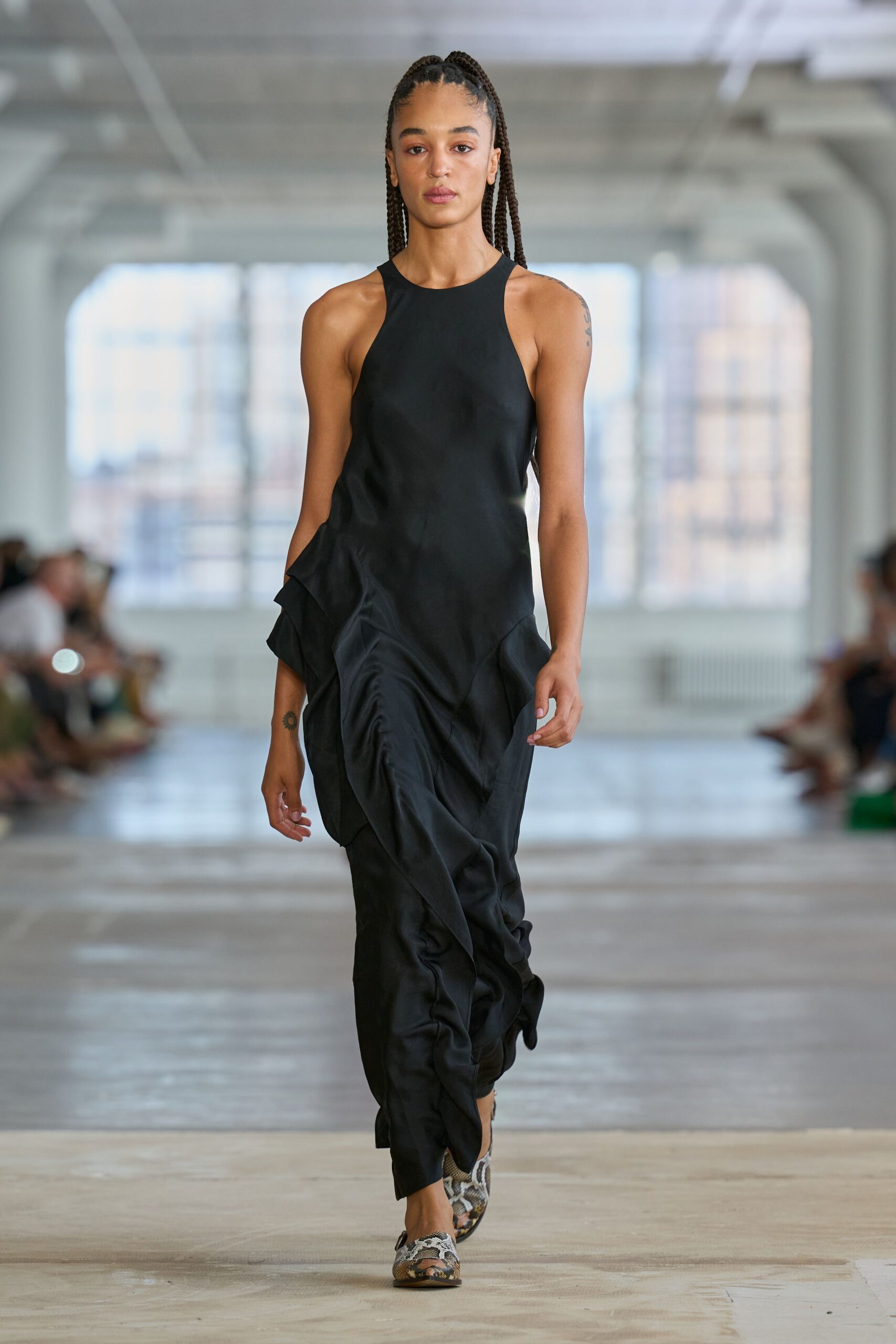 Black satin column dress with a high racer front and gathered ruffle seams twisting low. Python-print pointed flats, cut low across the vamp. Crossing a hotel lobby at noon after sleeping in yesterday's makeup.