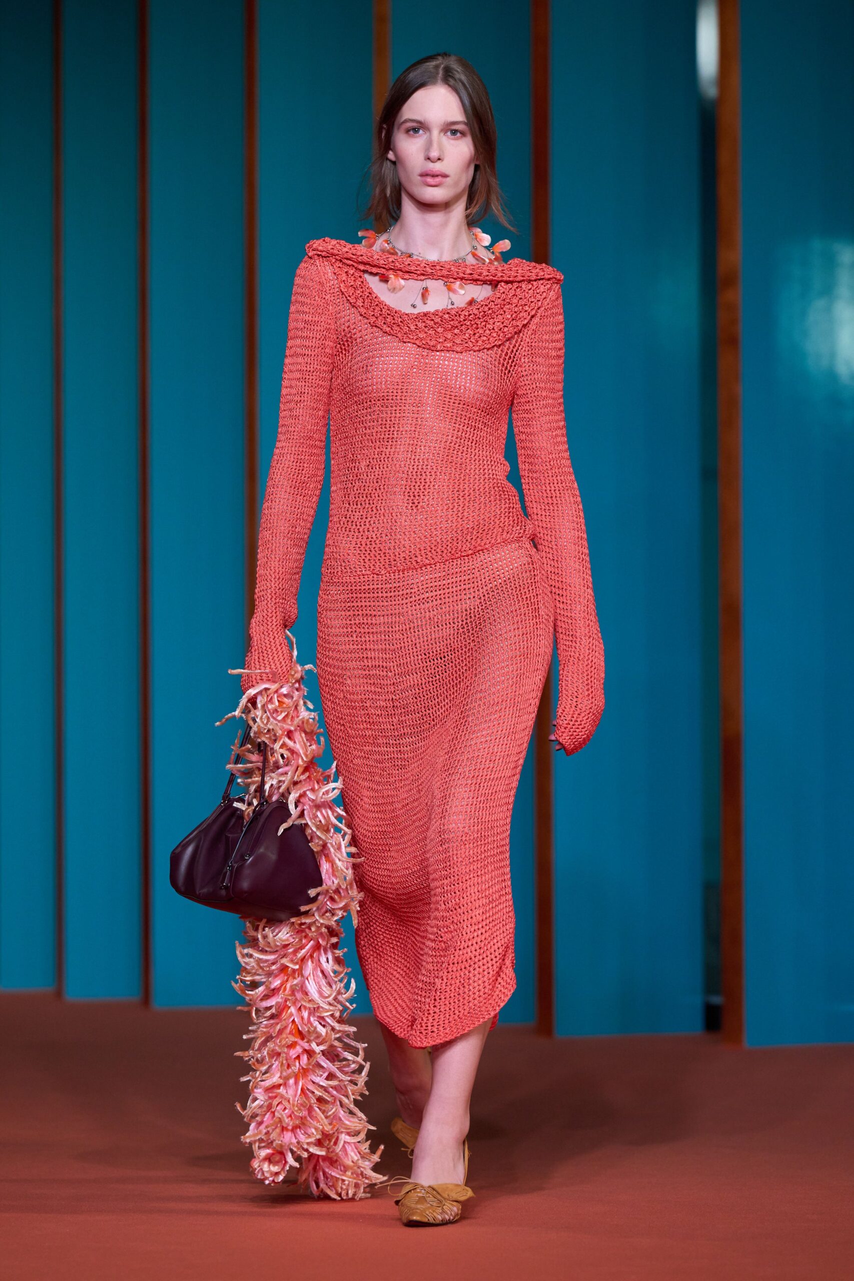 Coral open-knit dress with a rolled cowl collar and slanting hip seam. Petal-like pink drops scattered on a fine chain. Burgundy leather handbag trailed by a long pink raffia fringe. Tan ruched flats with a tiny bow at the toe. Walking back from a seaside lunch with wet flowers tangled to your bag.