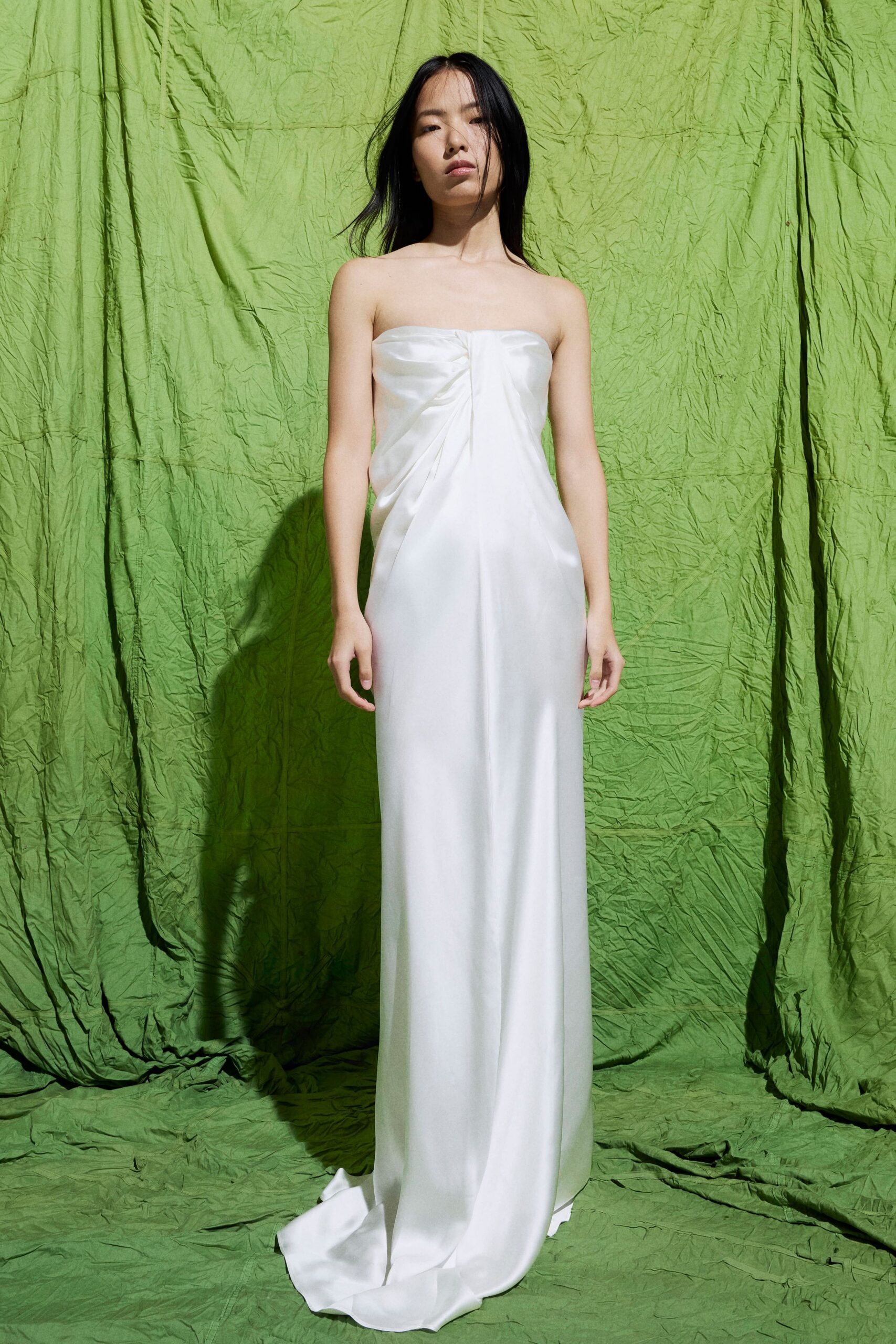Strapless white satin column gown, softly ruched at the center bust and pooling at the hem. Courthouse wedding, then cutting through the park before anyone finds you.