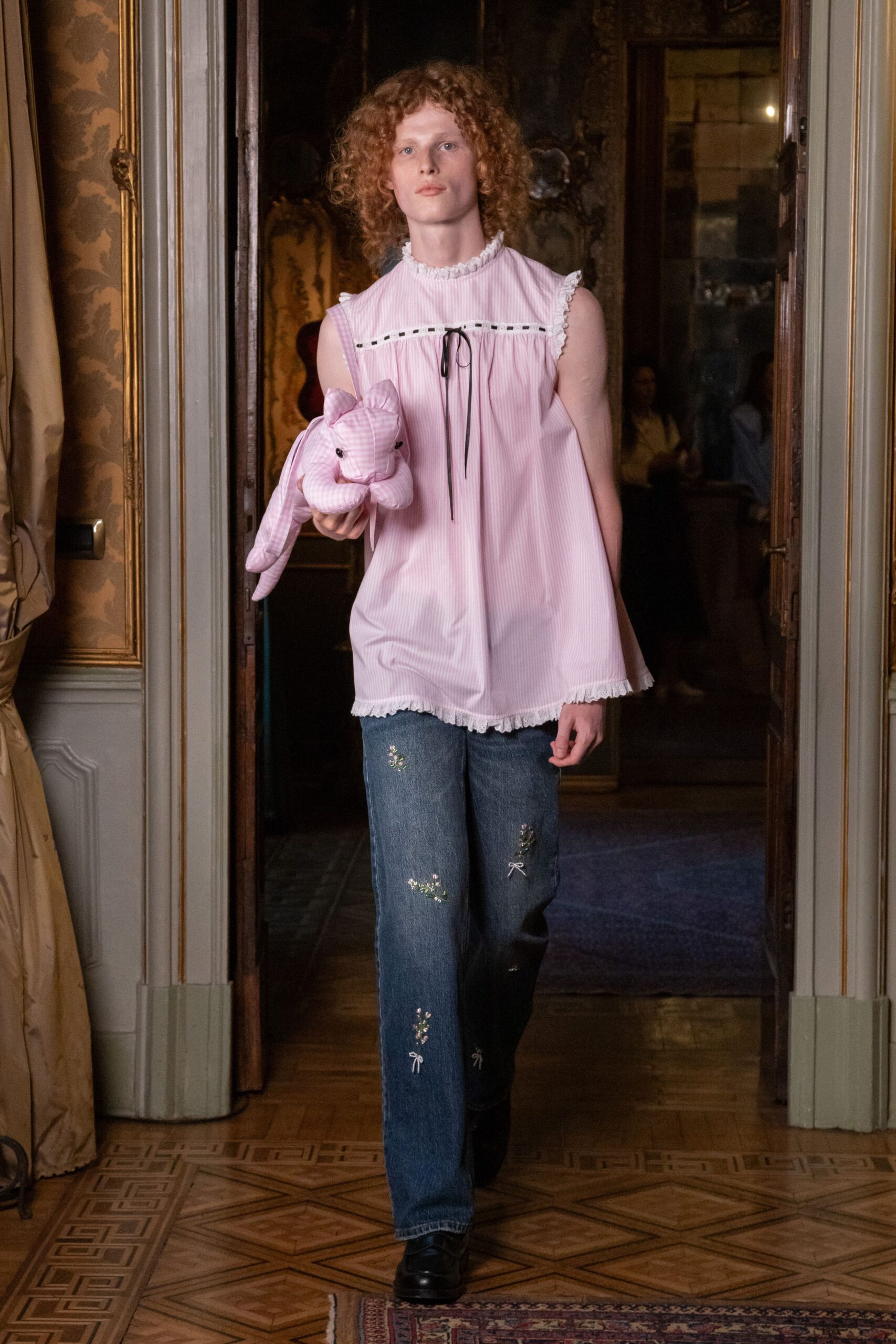 Pale pink striped cotton smock, ruffled edges and black ribbon at the yoke. Matching striped plush rabbit tucked under one arm. Straight blue denim embroidered with tiny sprigs and bow-tied stems. Black leather shoes with a heavy rounded toe. Leaving a childhood bedroom during Easter at the grandparents' house.