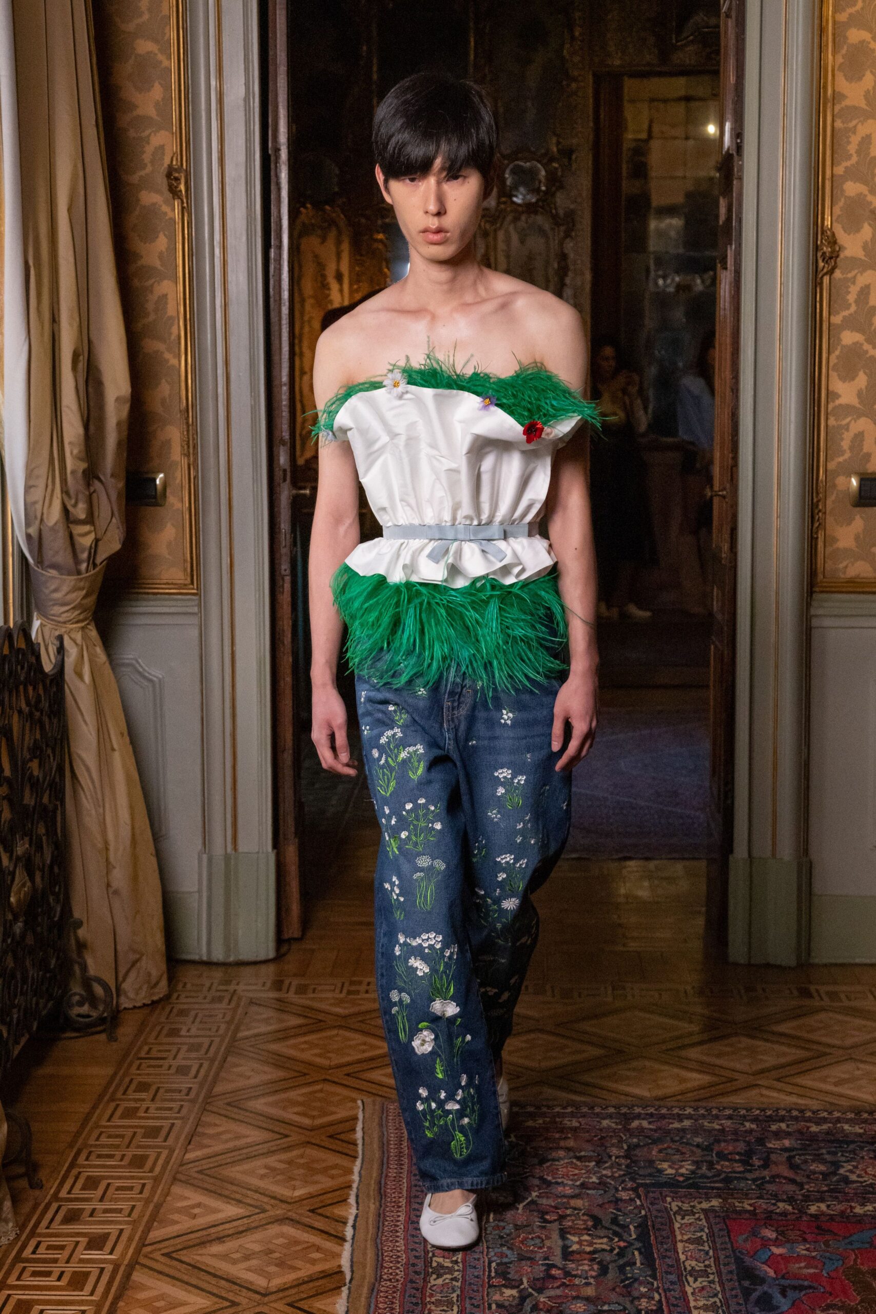 White strapless poplin top, crumpled and cinched with green ostrich trim. Powder-blue ribbon belt tied in a flat bow. Straight blue denim embroidered with scattered wildflowers and thin green stems. White ballet flats with a narrow vamp. Crossing a parquet salon after stealing flowers from the garden.