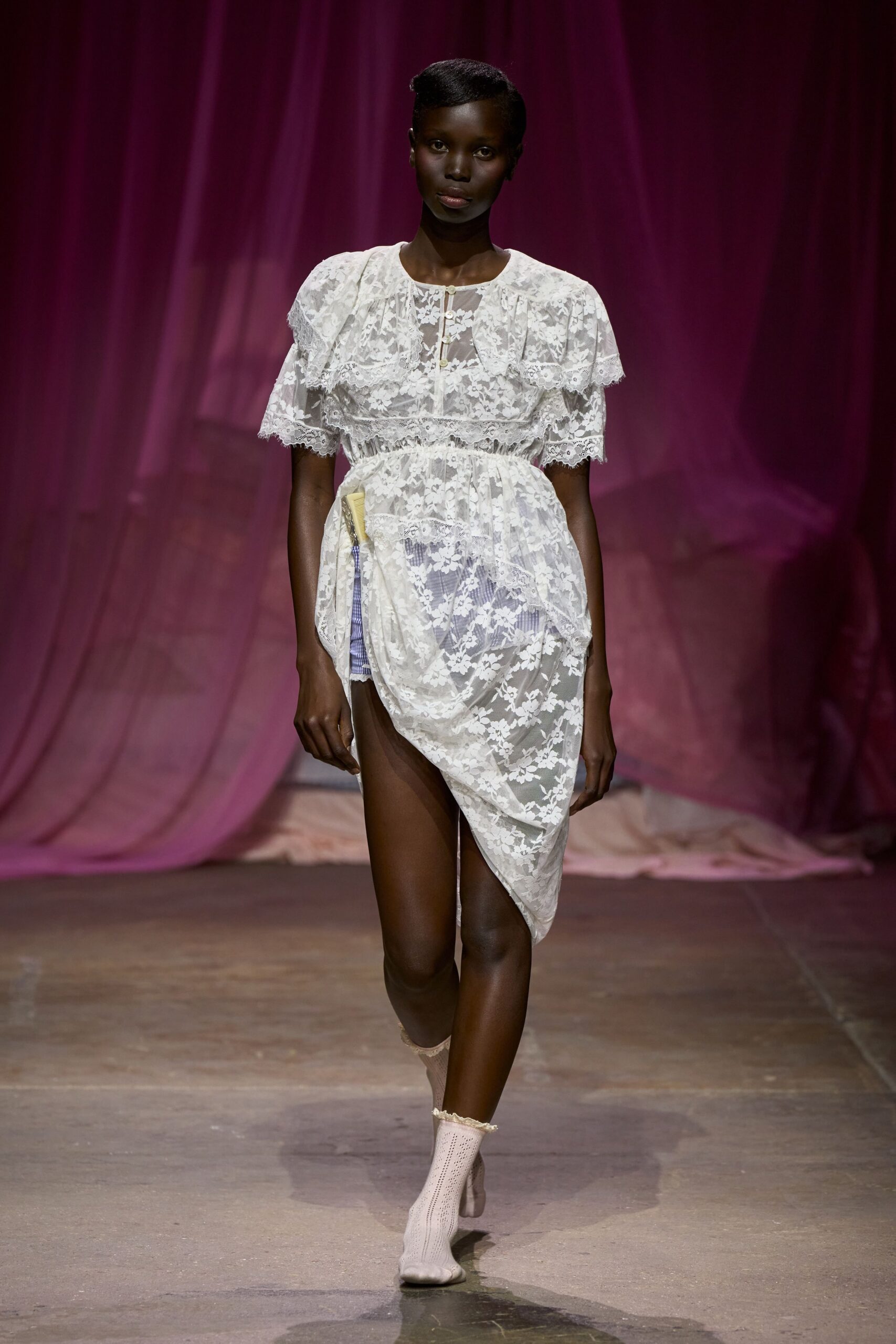 White floral lace dress with capelet ruffle and one side hitched high. Pale striped shorts peeking from beneath the sheer drape. Openwork ankle socks with scalloped edges. Walking back from the lake house porch before the sheets are dry.