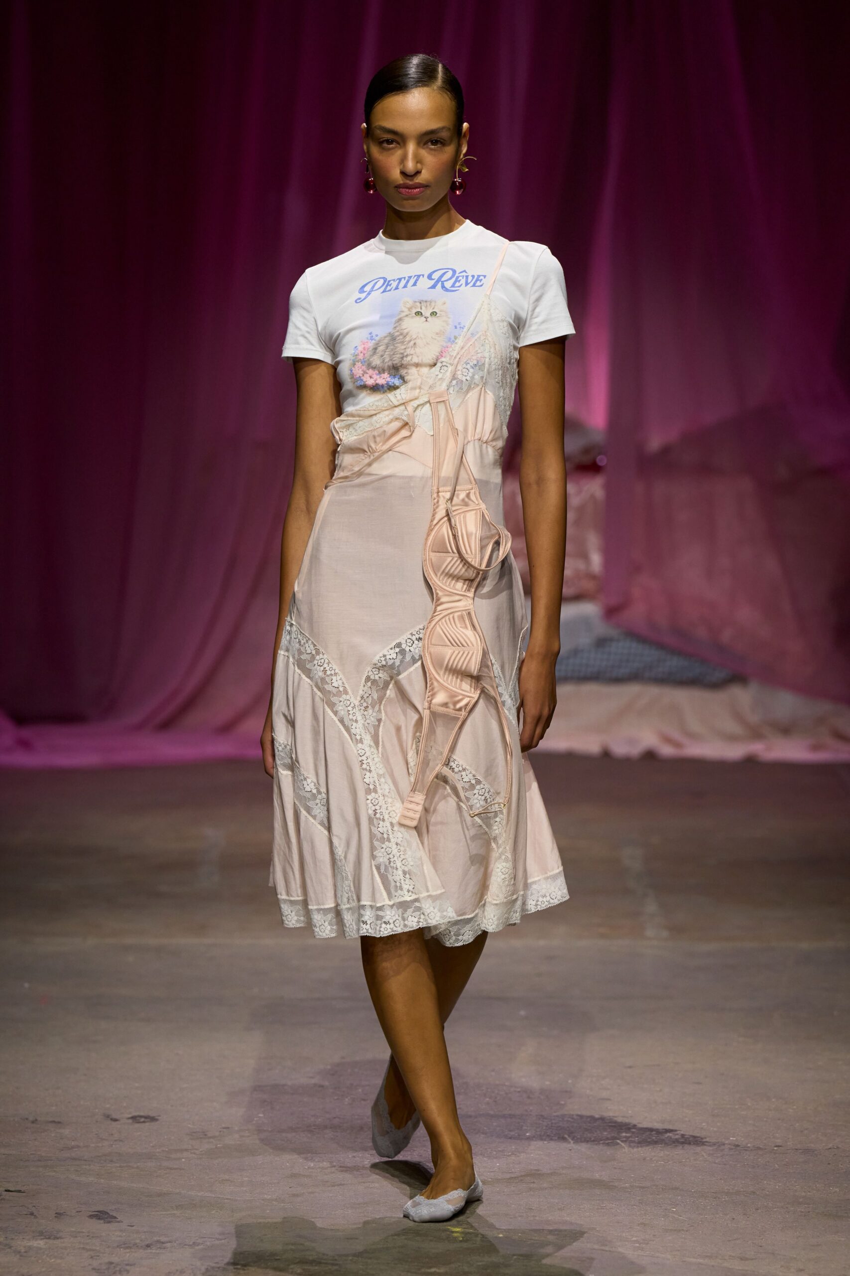 White fitted tee printed with a long-haired kitten and lavender script. Blush slip dress in sheer voile, pieced with slanting white lace. Pale satin bra strapped over the dress, one cup hanging low. Powder blue lace flats. Sunday morning in a bedroom with the curtains still drawn.