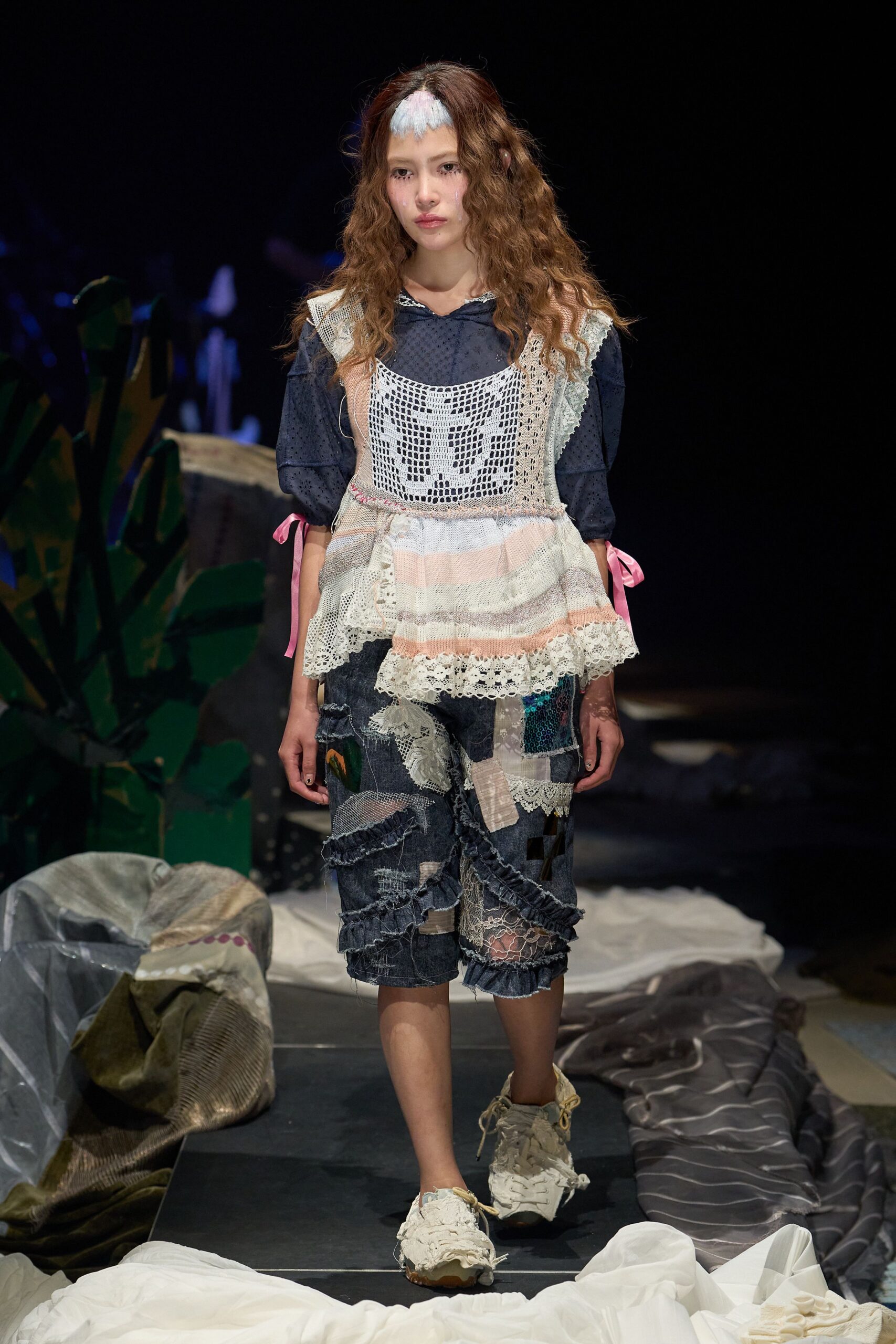 Navy swiss-dot blouse under a pastel striped knit pinafore with a crochet bib and pink ribbon ties at the sleeves. Patchwork denim shorts spliced with lace and sequins, frayed sneakers. Like raiding a beach cottage attic during a power cut.
