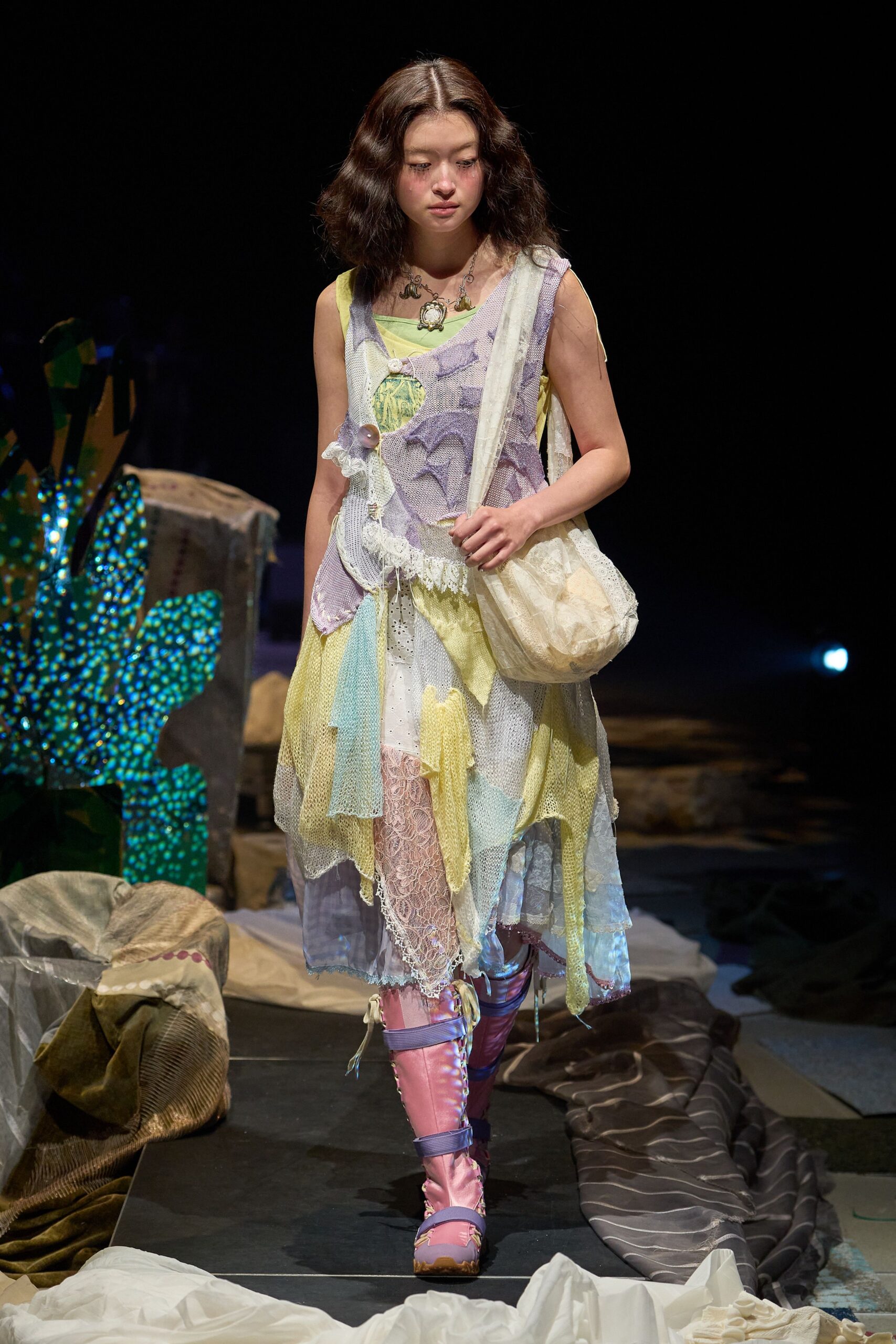 Patchwork mesh slipdress in lemon, lilac and powder blue, hung with eyelet lace and one oversized button at the bust. Cream gauze shoulder bag, pink lace stockings, lavender-strapped satin boots. Like dawn at a seaside arcade after the lights cut.