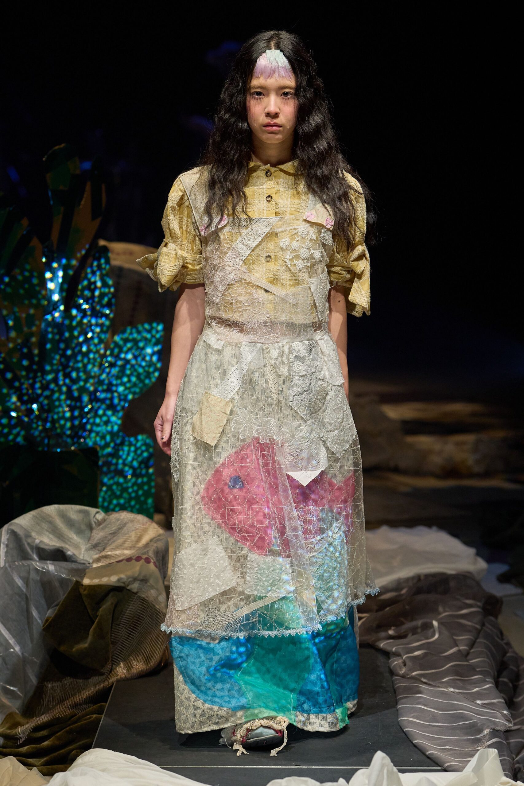 Yellow plaid shirt with puckered weave and sleeves knotted at the bicep, under a sheer patchwork lace pinafore dress with slips of tulle and a little pocket hanging askew. Like dressing from a sewing-room floor at dusk.