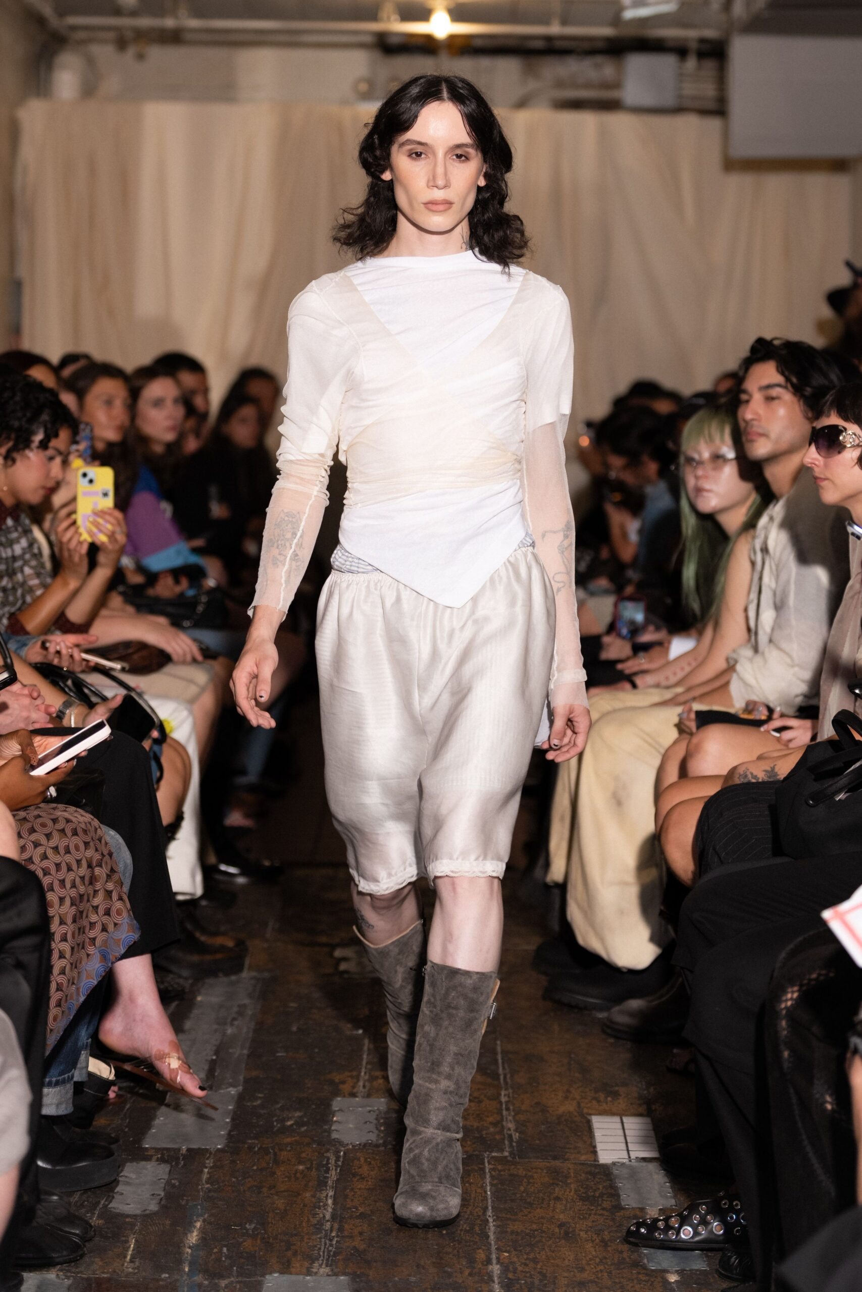 Ivory mesh top, ruched on the diagonal with one sheer short sleeve. Pearly silk bloomers cut below the knee, lace edging peeking out. Slouchy ash-suede boots with rubbed toes. Walking back from the bathhouse with wet hair under a borrowed coat.