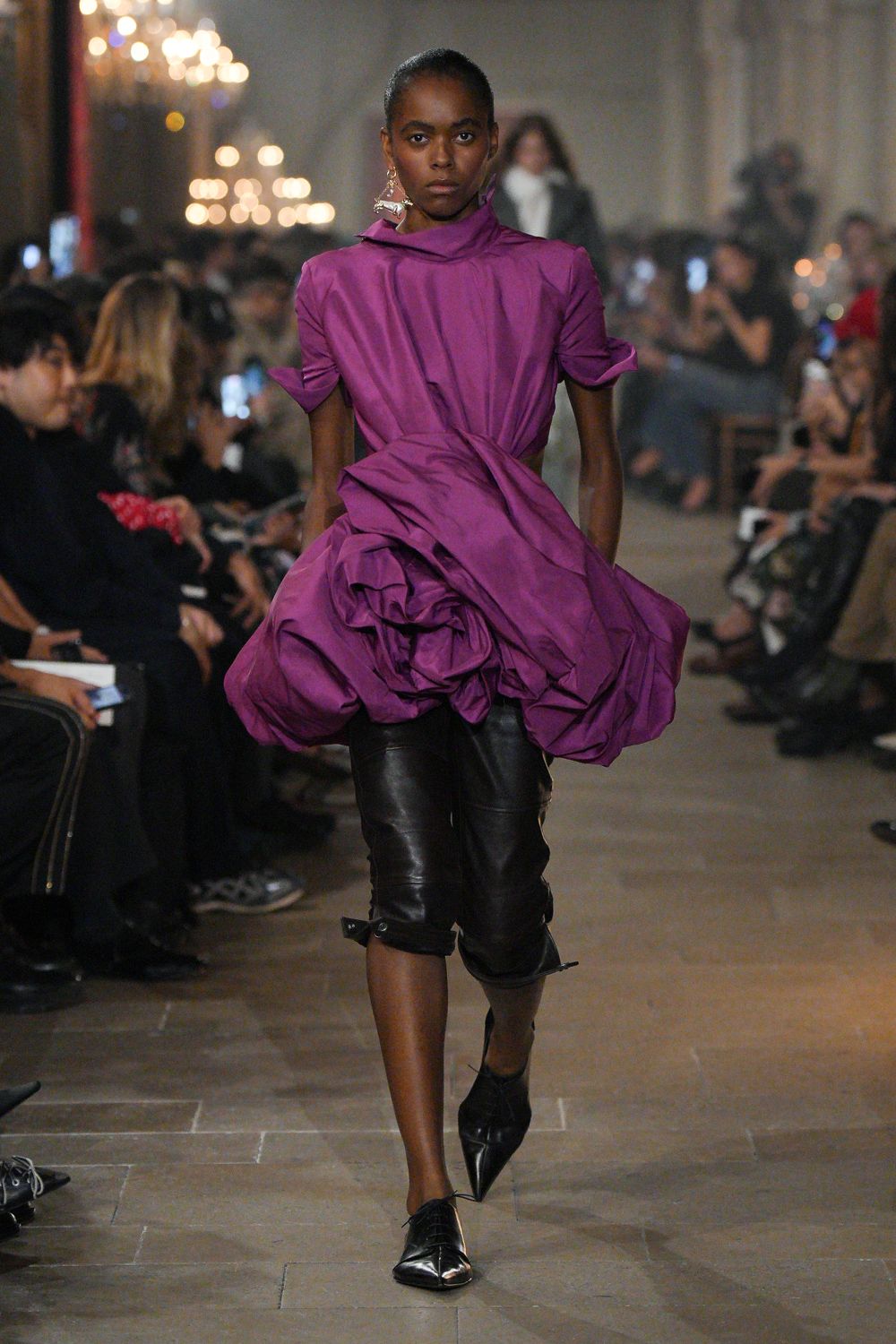 Magenta taffeta dress, high funnel neck and a huge rosette-bustled hem. Black leather capris, buckled straps left hanging at the calves. Mismatched silver danglers. Black pointed pumps with a creased vamp. Crossing a candlelit hall after knocking over the centerpiece.