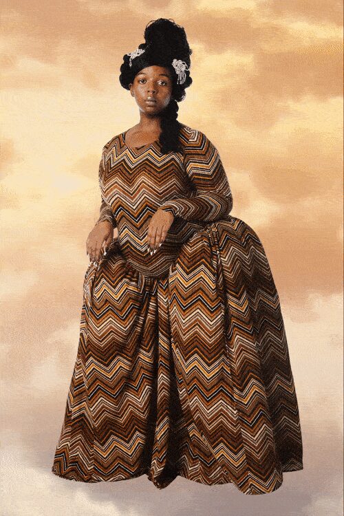Black wrapped headpiece pinned with two silver rosettes. Voluminous chevron-woven gown in tobacco, cream and rust, sleeves ending in puffed cuffs. Portrait sitting after rain, the backdrop still the color of wet plaster.