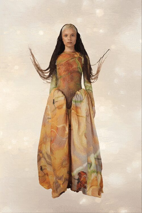 Second-skin bodysuit airbrushed in moss and rust, sleeves fading sheer. Voluminous parchment skirt printed with blown-up florals, gathered into hip swags. Black lengths draped like a mantilla, ends wired outward. Crossing a winter garden after dark with pollen still on your cuffs.