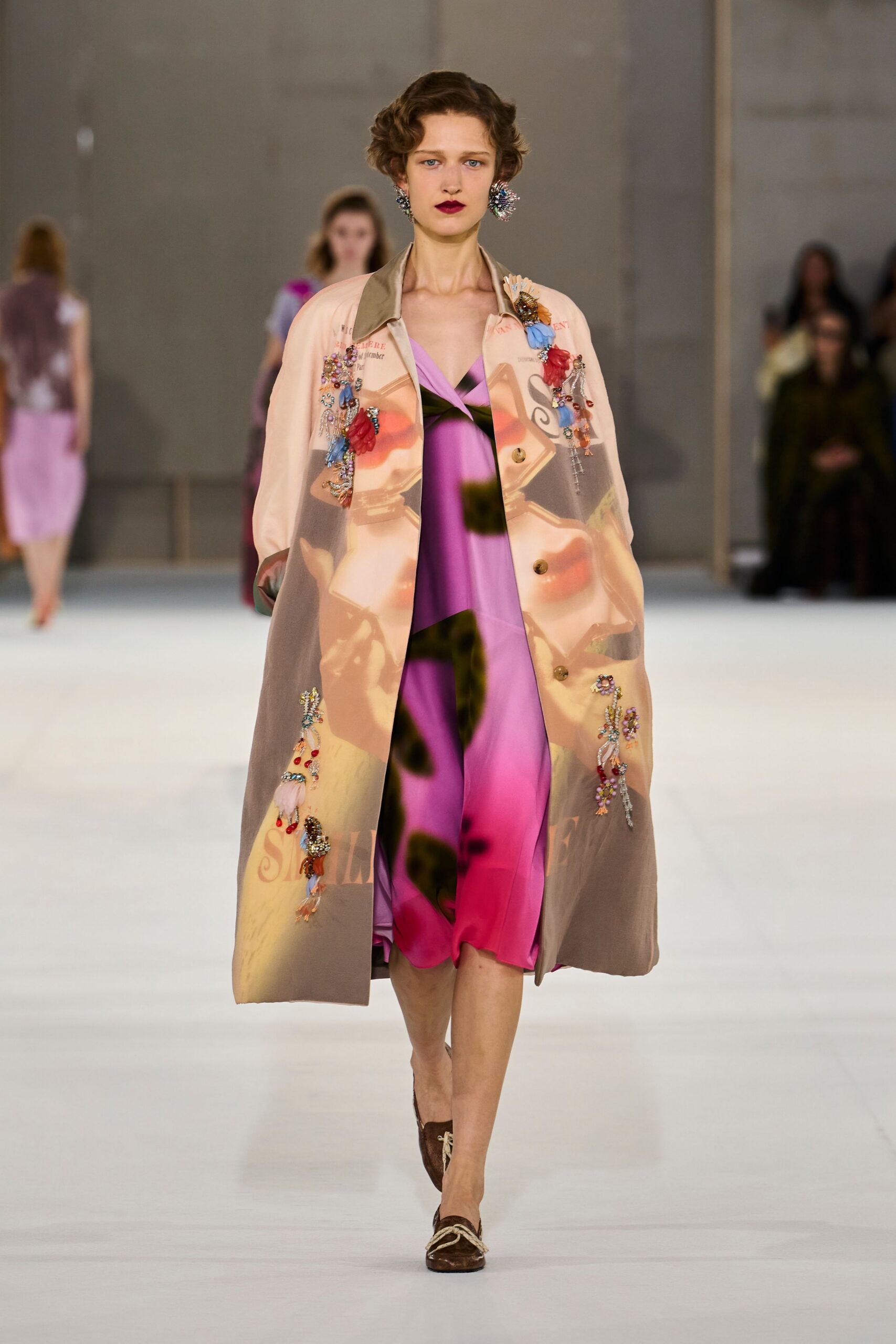 Spiky crystal cluster earrings, almost shoulder-brushing. Sheer printed duster scattered with jeweled appliques and dangling beaded tassels. Fuchsia slip dress with black vine blurs and a twisted neckline. Brown velvet loafers tied with thick cream cord. Crossing a museum atrium with florist ribbons still caught on your coat.