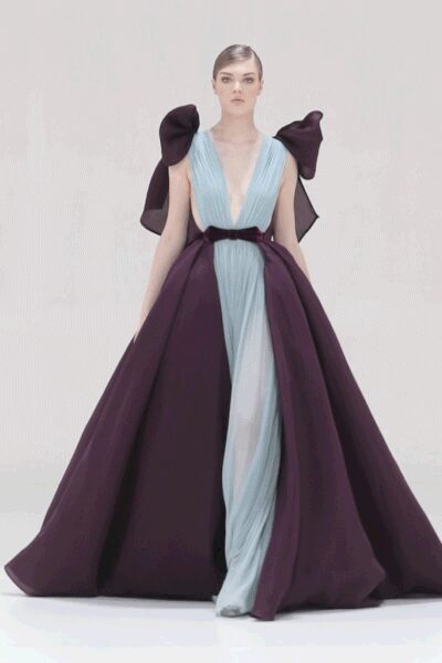 Ice-blue chiffon gown with a plunging ruched bodice and narrow black waist. Deep aubergine overskirt opening from the belt into a stiff cathedral sweep. Huge wired bows perched at each shoulder. At the top of a marble staircase after everyone else has gone down.