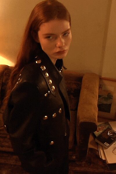 Black leather biker jacket punctuated with large silver dome studs along the lapels. Hotel lamplight after midnight, someone else's magazine still open on the chair.