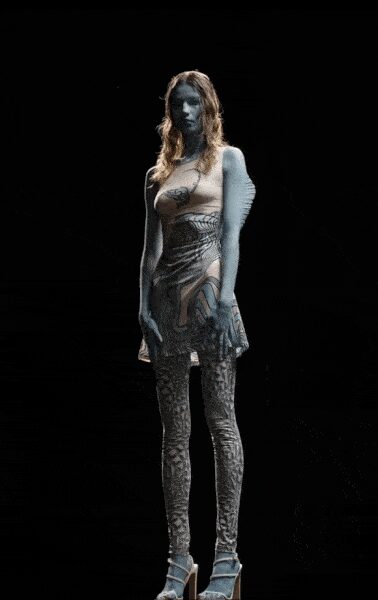One-sleeve nude mesh mini, octopus print curling across the torso. Pale snake-pattern tights, dense from hip to pointed toe. Chunky ankle-strap platforms with a heavy block heel. Aquarium tunnel after closing, still carrying the blue light.