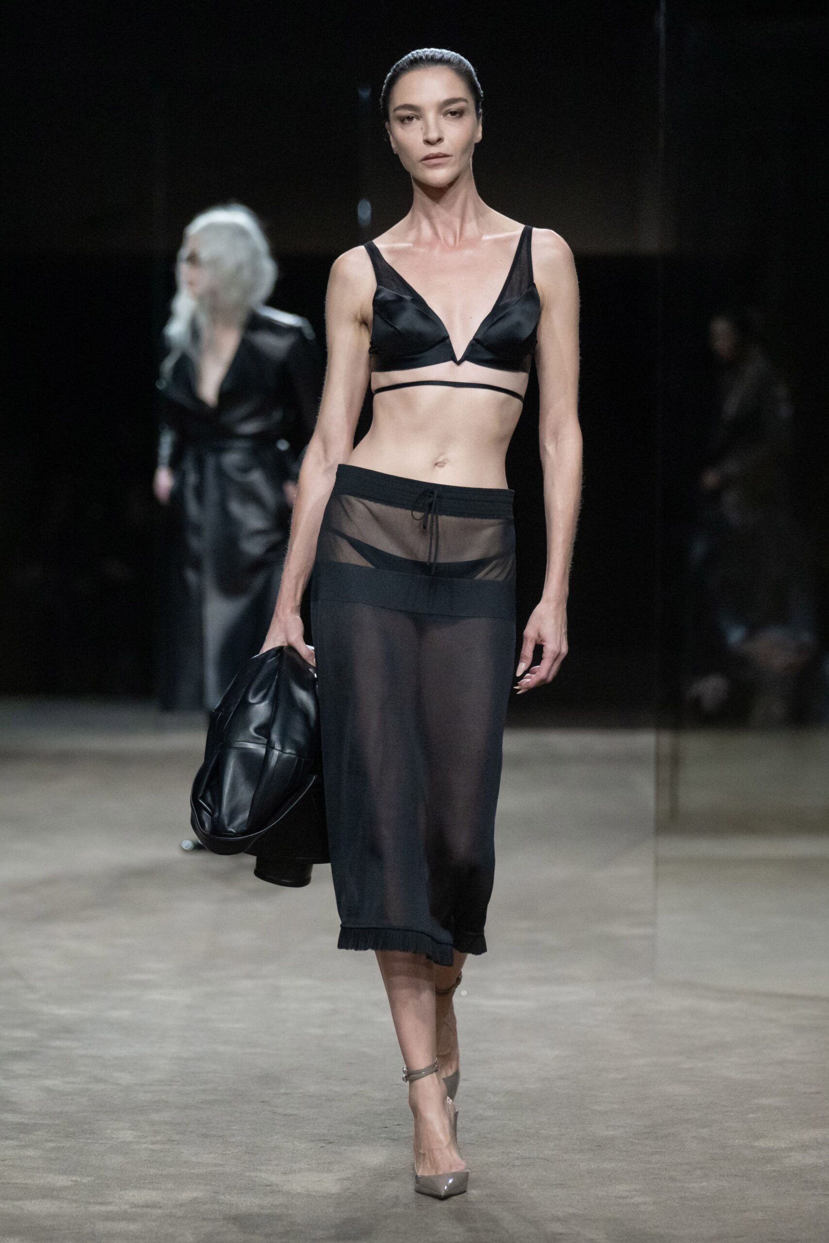 Black satin bralette with a sharp V notch between the cups. Sheer black mesh midi skirt, drawstring waist and ribbed hem. Slouchy black leather clutch tucked under one arm. Grey patent pointed pumps with clear ankle straps. Whatever you wear home when the hotel pool is empty by dawn.